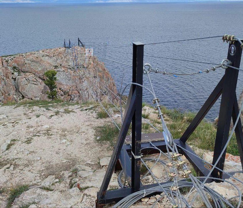 Никаких аттракционов на святыне Ольхонский районный суд обязал дирекцию особо охраняемых природных территорий Заповедное Прибайкалье убрать навесной мост на мысе Саган Хушун на острове Ольхон Он появился там летом прошлого года Тогда в администрации нацпарка говорили что работы идут по программе благоустройства туристического места На мысе планировали сделать поверхностные незаглубленные настилы для пешеходов организовать там инфоцентр для туристов парковку биотуалеты подвесные воздушные конструкции беседки качели и смотровую площадку За работы взялась крымская региональная общественная организация Фрирайт которая оборудовала подвесной мост на горе Ай Петри в Крыму  Но местные жители посчитали это вандализмом и оскорблением чувств верующих Устанавливать мост начали в начале июля Тревогу забила экскурсовод по Ольхону Анита которая считает что нельзя поступать так со священными местами Невозможно смотреть на то как скалы которым миллион лет сверлят Это особое место для жителей Ольхона считается что здесь обитают духи и их нельзя тревожить После этого в Хужирской администрации собрали подписи под петицией об остановке монтажа подвесного моста Выездная бригада Фрирайта повесила временный мост который и увидели активисты но на самом деле это смонтировали на местности чтобы передать проект на рассмотрение специалистам научного отдела Заповедного Прибайкалья и службе по охране объектов культурного наследия Иркутской области Реализация проекта может быть только после их заключений Заповедное Прибайкалье уже штрафовали на 300 тысяч рублей за нарушение требований об охране объектов культурного наследия Подписаться