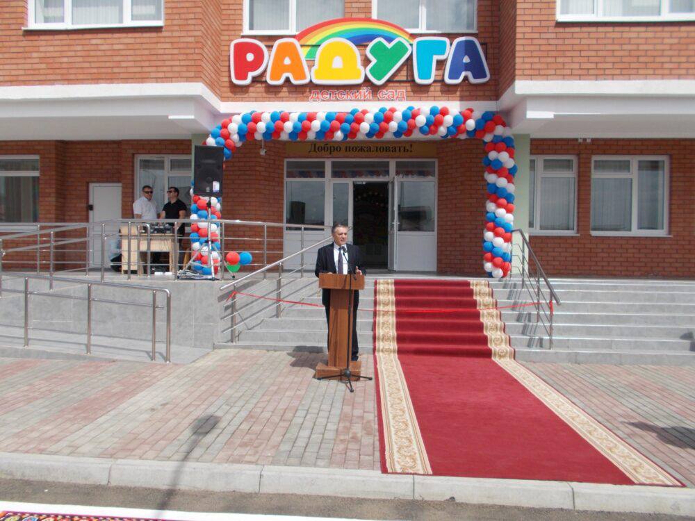 Новый детский сад «Радуга» распахнул свои двери В селении Нижнее Казанище Буйнакского района состоялось значимое для местного сообщества событие – открытие нового дошкольного образовательного учреждения «Радуга». Этот детский сад стал третьим по счету в населенном пункте и полностью соответствует современным стандартам качества дошкольного образования. Развитие социальной инфраструктуры села становится особенно актуальным в условиях активного роста населения. Численность жителей Нижнее Казанище приближается к 20 тысячам человек, и значительная часть прироста приходится на молодые семьи. Новый детский сад построен в перспективном районе, где ведется активное жилищное строительство, что позволит эффективно решать вопросы дошкольного образования для подрастающего поколения и способствовать улучшению качества жизни семей. Современное дошкольное учреждение рассчитано на 90 воспитанников. Инфраструктура детского сада продумана до мелочей: просторная территория оснащена современными игровыми площадками, обеспечивающими безопасное и увлекательное времяпрепровождение детей. Внутреннее пространство включает все необходимые помещения: уютные спальни для дневного отдыха, современную пищеблок и просторную актовый зал, где будут проходить праздники и развивающие мероприятия. Открытие детского сада «Радуга» является важным шагом в развитии социальной инфраструктуры района и способствует решению актуальных задач по обеспечению доступности дошкольного образования для жителей Нижнее Казанище. Торжественное открытие дошкольного учреждения привлекло внимание представителей высшего руководства республики. В церемонии приняли участие заместитель председателя Правительства Республики Дагестан Абдурахман Махмудов, министр труда и социального развития РД Магомедзагит Кихасуров, заместитель Председателя Народного Собрания Республики Дагестан Руслан Ибрагимов, первый заместитель министра образования РД Аида Далгатова и начальник аппарата администрации Буйнакского района Элдар Гасанханов.