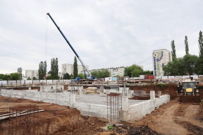 В Красногорском районе Каменска-Уральского идет возведение легкоатлетического манежа. Строительные работы начались полтора месяца назад и идут по графику. Согласно муниципальному контракту, работы должны быть завершены не позднее февраля 2027 года Накануне площадку посетил глава города Алексей Герасимов. Сейчас на объекте завершаются земляные работы. Строителям предстоит заменить песком около 6 тыс. кубометров грунта, непригодного для основания. Задействовано 11 единиц техники. В финальной стадии и заливка фундамента. Также параллельно идет подвод сетей водоснабжения. К концу года, по словам подрядчика, будет готова коробка здания. Внутренняя отделка и оснащение манежа оборудованием запланированы на 2026 год. У легкоатлетического манежа будет собственная котельная. Ее проект готов и сейчас проходит госэкспертизу. Котельную построят и запустят к отопительному сезону 2026–2027 годов. пресс-служба Каменск-Уральского городского округа Подписаться на «ОГ» Прислать новость Поддержать канал
