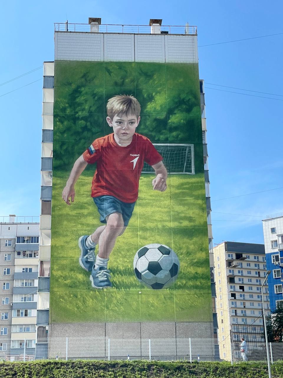 Юного футболиста изобразили на фасаде многоэтажки в Красноярске Мурал появился в микрорайоне Солнечный на доме № 23 по проспекту Молодёжный. Неподалеку находится школьный стадион. Руководитель агентства печати и массовых коммуникаций Красноярского края Ирина Брежнева рассказала, что в ближайшее время приступят к работе над еще одним муралом. Он разместится на доме в микрорайоне Пашенный. Фото: Ирина Брежнева