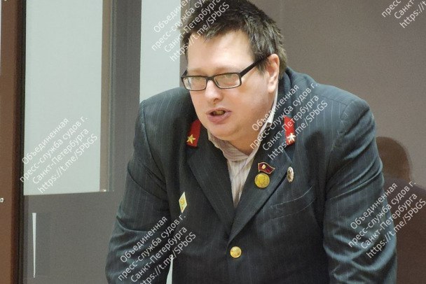 По-учительски навис над столом, подходил к судье. В Петербурге давали шоу сталиниста-ортодокса  Как сообщила объединенная пресс-служба судов Петербурга, городской суд назначил год и 8 месяцев лишении свободы в колонии-поселении Дмитрию Денисову. Он признан виновным в эпизодах реабилитации нацизма с помощью публикаций в глобальной сети.  По данным пресс-службы судов, в 13:11 15 января подсудимый Денисов в сообществе "ВКонтакте" оставил комментарий. Его трактовали как приравнивание современной Российской Федерации, конституционных принципов, президента к лидерам и системе устройства нацистской Германии и их пособникам. К записи был прикреплен портрет Гитлера, размещенный с помощью монтажа среди портретов "Бессмертного полка".  Сам Дмитрий Денисов сообщил суду, что получил педагогическое образование, но работу найти не смог. Пришлось повышать квалификацию. Речь произносил оперевшись кулаками на стол. В целом подсудимый не отказывал себе в перемещениях, подошел к судье с пачкой документов и прервался, чтобы отменить входящий вызов на мобильный телефон. В зал Денисов пришел в пиджаке, стилизованном под бушлат военачальника времен Сталина.  Подсудимый вину признал частично. Исследованные доказательства не оспаривал, а сам себя назвал ортодоксальным коммунистом и сталинистом.     Объединенная пресс-служба судов Петербурга