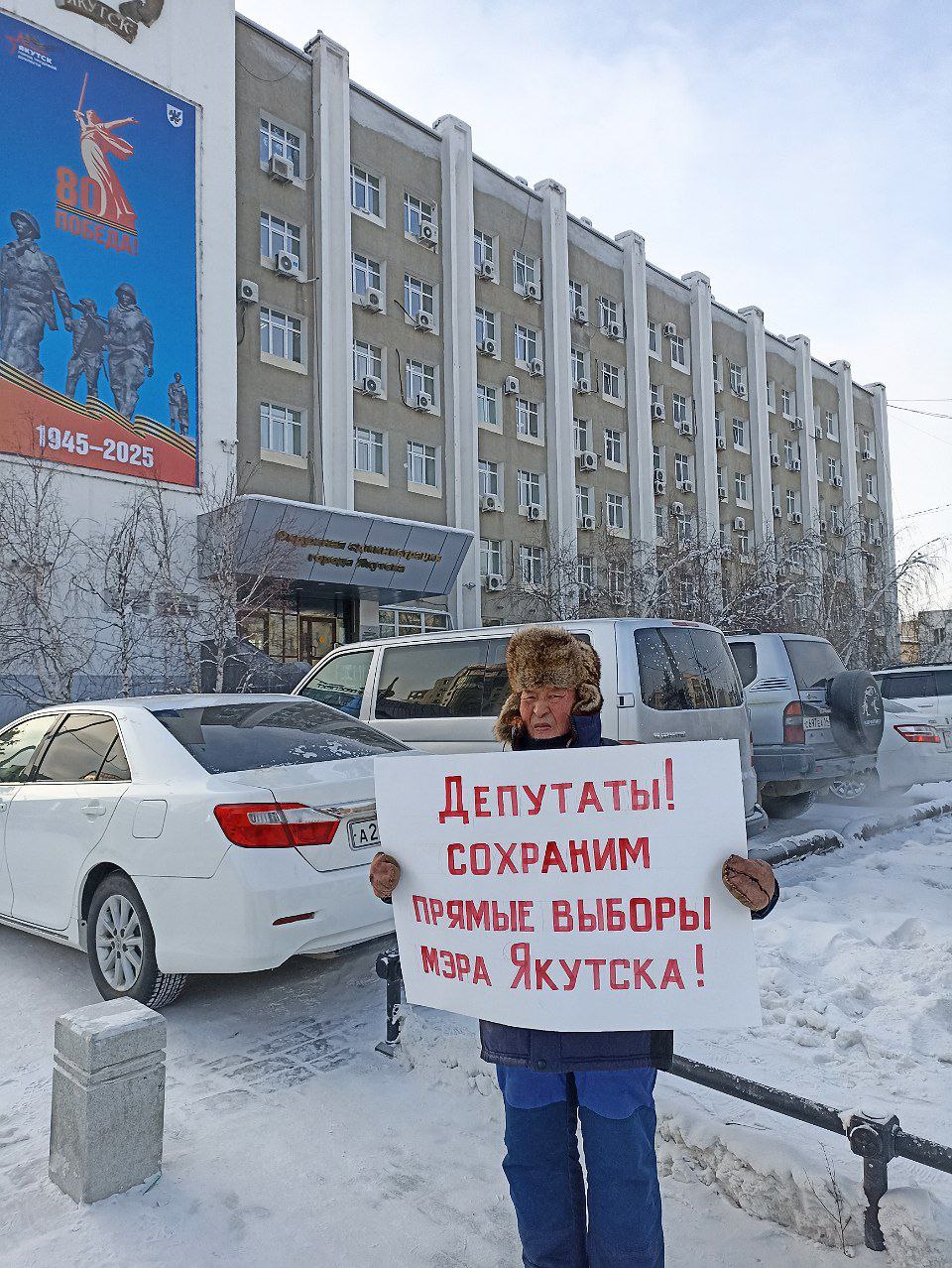 Одиночный пикет возле мэрии Якутска проводит неизвестный гражданин. Представиться отказался.   Митинг приурочен к 13-й внеочередной сессии Якутской Гордумы, на которой будет рассмотрена и скорее всего принята законодательная инициатива об отмене прямых выборов мэра городского округа.