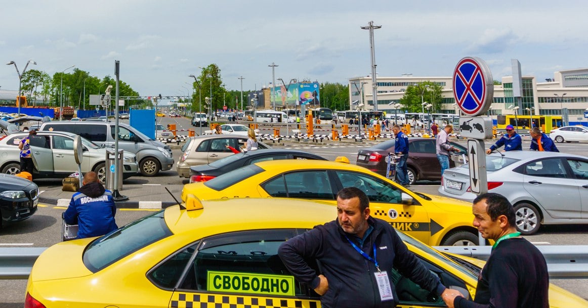 В московских аэропортах заработали ограничения для таксистов-зазывал  Вступило в силу резонансное постановление правительства Подмосковья о запрете на услуги такси без официальных стоек. Предполагается, что теперь таксисты-зазывалы не будут налетать на пассажира как коршуны при выходе из аэропорта, а должны будут оказывать услуги в здании.  У пассажира теперь, согласно правилам, есть две опции: заказать такси через агрегатора или обратиться на официальную стойку в аэропорту, где вам закажут машину и дадут всю информацию о стоимости поездки. За месяц Минтранс должен выпустить единые требования к оформлению таких стоек такси. Пока их нет.  Изменения касаются аэропортов Шереметьево, Домодедово и Жуковский — они расположены на территории Подмосковья. Внуково же находится на территории Москвы и, кажется, под действие областного постановления не подпадает. Что весьма странно, ведь у властей Москвы и области принято принимать похожие решения совместно.