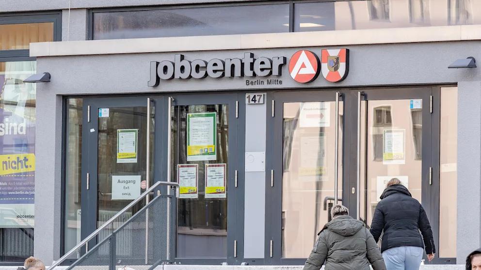 В Германии вводят новую систему пособий для безработных которая должна стать жестче чем Bürgergeld С 1 июля 2026 года в Германии вместо Bürgergeld для трудоспособных безработных вводят новую систему Grundsicherung базовая поддержка В правительстве уже заявляют что она будет значительно строже Bürgergeld Речь идет примерно о 3 87 млн человек именно столько получателей нынешнего пособия считаются трудоспособными и автоматически перейдут на новую модель Размер выплат при этом не меняется 563 евро в месяц для одного человека 506 евро для партнера и от 357 до 471 евро для детей Государство как и прежде будет полностью оплачивать аренду и отопление поясняет Федеральное министерство труда Главное отличие санкции Теперь уже за первое нарушение обязанностей пособие могут сократить на 30 После трех пропущенных визитов в центр занятости выплаты прекращаются полностью Если человек более четырех недель не выходит на связь государство перестает платить и за жилье Для сравнения при Bürgergeld штрафы начинались с символических 10 Украинские беженцы прибывшие после апреля 2025 года будут получать уже не Grundsicherung а более низкие выплаты для соискателей убежища Граждане Украины которые приехали в Германию раньше и подались на беженство останутся в новой системе BILD Russian