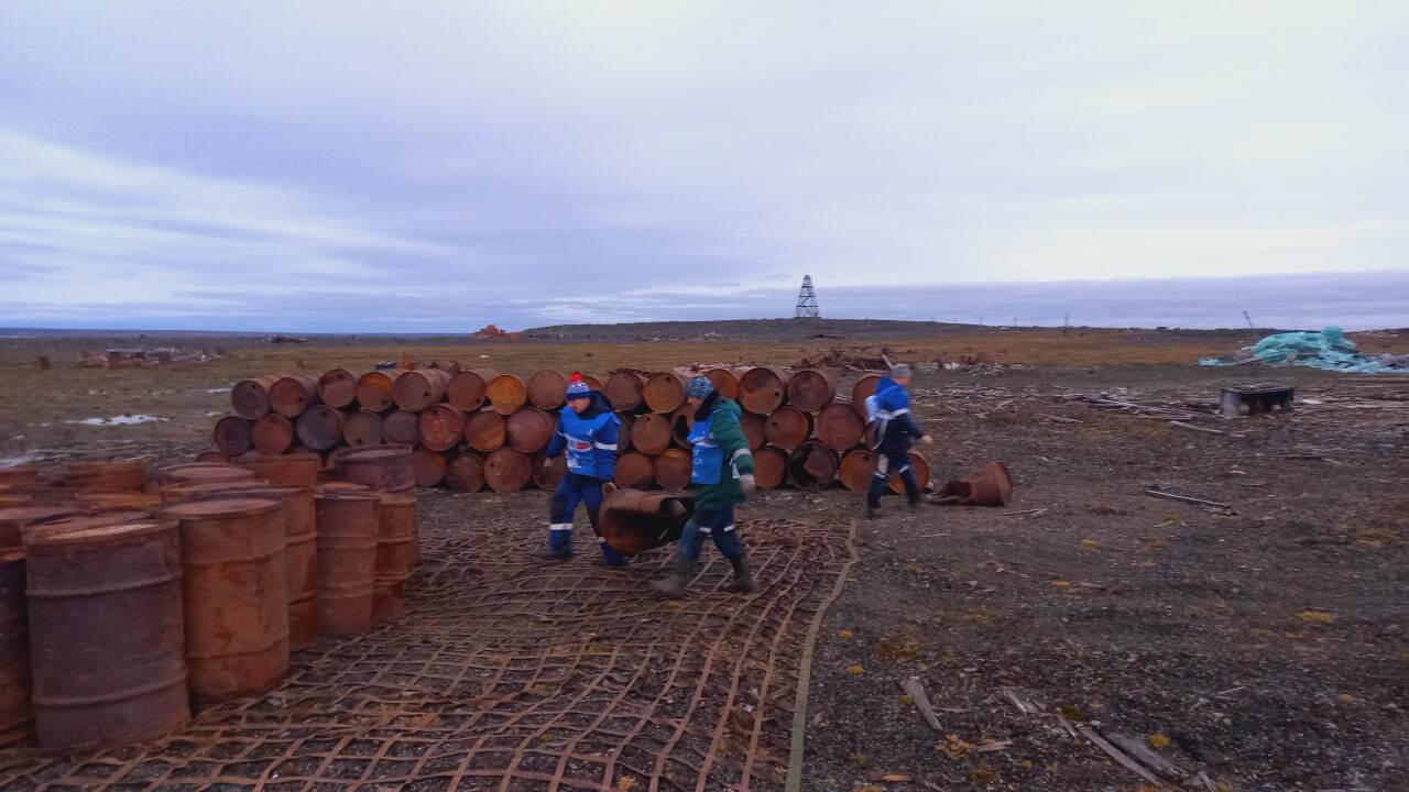 На мысе Челюскин волонтёры Чистой Арктики подготовили к погрузке на судно 800 пустых железных бочек из под горюче смазочных материалов Отгружаются они сетками по 50 80 штук поскольку за один раз вертолет может поднять 2 5 тонны груза Чтобы не повредить тундровую поверхность волонтеры катали бочки вручную важной задачей было успеть собрать емкости до наступления минусовых температур которые прогнозируются уже к концу этой недели рассказали в организации Бочки десятилетиями накапливались в Арктике Только на площади в 40 га на мысе Челюскин скопилось порядка 40 тысяч бочек с ГСМ Кроме того там лежит множество металлолома от старой техники советского периода
