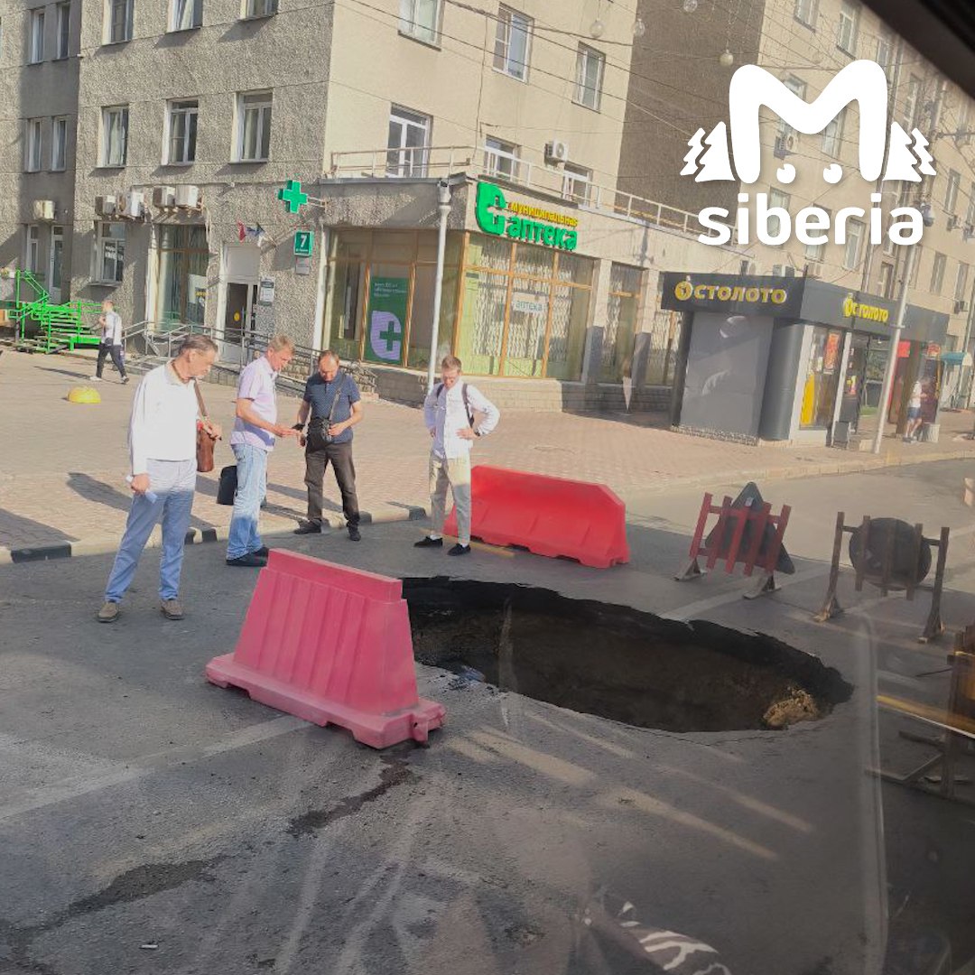 Огромный провал образовался на Красном проспекте в Новосибирске. Яму огородили, пешеходы уже фотографируют её как местную достопримечательность. UPD. Дыру засыпали.