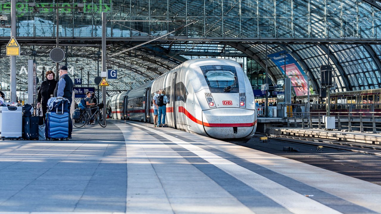 Проблема железных дорог Германии Deutsche Bahn DB это уже общеевропейская беда Когда то развитие ж д инфраструктуры помноженной знаменитая немецкая пунктуальность и педантичность давали экономике Германии заметное преимущество Сейчас же это якорь который тащит на дно не только Германию но и весь Евросоюз зависящий самочувствия немецкой экономики Дело в катастрофической бюрократизации Deutsche Bahn Недавние расследование немецких журналистов показало эпидемия опозданий и отмены поездов имеет которой две причины и обе связаны с излишней внутренней регуляцией Во первых это диктатура профсоюзов постоянно улучшающих и усложняющих условия работы сотрудников DB В результате жестких ограничений переработок увеличения технических перерывов а также бюрократизации внутренних процессов снижается объем рабочих часов связанных с непосредственным выполнением рабочих обязанностей сотрудников Это приводит к нехватке трудовых ресурсов что выливается в опоздания и отмены рейсов Во вторых руководство DB часто отменяет поезда которые удалось укомплектовать штатным количеством сотрудников но они опаздывают Дело в том что отмененные поезда не попадают в статистику опоздавших а к опозданиям привязаны премии руководства Der Spiegel приводит пример как 16 сентября один из скоростных поездов следовавший по маршруту Мюнхен Гамбург был отменен примерно на половине пути в Кельне К этому моменту он уже опаздывал более чем на час Официальная причина отмены неожиданная нехватка персонала Пассажирам пришлось менять планы и ждать следующего поезда по этому маршруту Однако за полтора часа до отмены в рабочем чате центра управления движением DB появилось сообщение Поезд отменяется от Кельна для улучшения статистики Der Spiegel отмечает что нередко отмененные поезда в итоге просто едут по стране пустыми Все это привело к жутким убыткам на данный момент долги DB составляют 22 млрд Кризис железных дорог пытаются ликвидировать Генеральный директор DB Рихард Лутц уже отправлен в отставку но пока исполняет обязанности поскольку продолжаются поиски преемника Должность считается расстрельной поскольку основные проблемы не представляются разрешимыми особенно на фоне бравурных заявлений политиков К примеру министр транспорта ФРГ Патрик Шнидер утверждает что к 2029 году удастся сократить долю опозданий поездов DB до 30 При этом издание Die Zeit утверждает что этот показатель значился во внутренних документах DB в качестве цели на 2026 год но она оказалась принципиально недостижимой Впрочем и новая не выглядит реалистичной уважаемые читатели