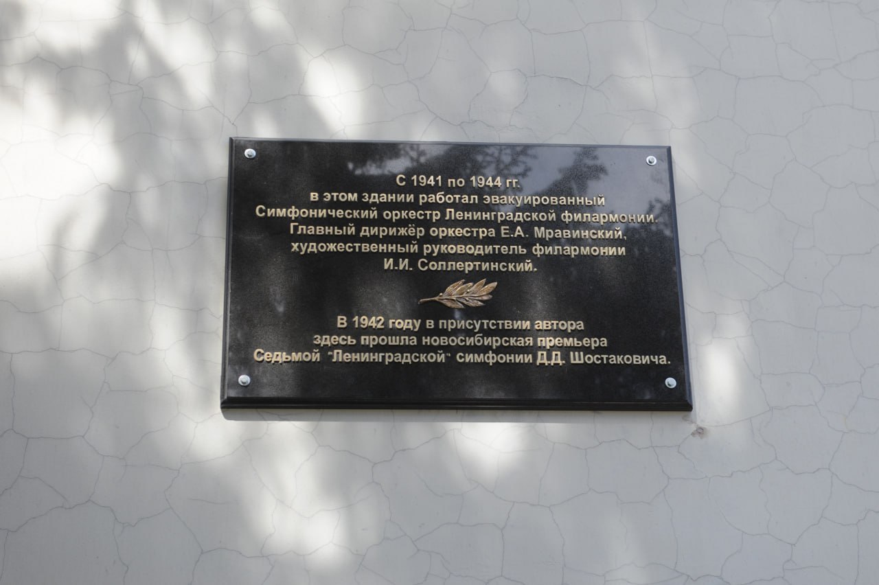 Церемония открытия обновленной мемориальной доски, посвященной двум знаковым событиям в истории Новосибирска В преддверии 80-летия со дня Великой Победы состоялся перенос и открытие отреставрированной мемориальной доски, посвященной симфоническому оркестру Ленинградской филармонии, работавшему с 1941 по 1944 гг. в здании Клуба имени Сталина ныне - ДК им. Октябрьской революции . На памятной доске также увековечено важнейшее историческое событие: в этом здании в июле 1942 года впервые за Уралом прозвучала Седьмая «Ленинградская» симфония Дмитрия Шостаковича в присутствии автора. С открытием памятной доски гостей мероприятия поздравил заместитель министра культуры Новосибирской области Юрий Зимняков. С приветственным словом выступил также директор Клуба Революции Алексей Крыжановский. Генеральный директор Новосибирской филармонии Анна Терешкова отметила, что сегодняшнее событие является ярким подтверждением тому, что культурные связи между городами и учреждениями продолжают жить и развиваться, ведь оно проходит в рамках совместного проекта Новосибирской и Петербургской филармоний «Мост через время: Ленинград - Новосибирск».