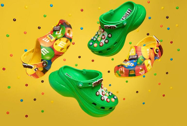 M M s и Crocs представили новую лимитированную серию сабо и джибитсов Коллекция поступит в продажу 9 октября она будет продаваться в 50 странах через онлайн платформы и официальных дистрибьюторов Всего будут доступны две модели сабо M M s Classic Clog и M M s Bae Clog и набор джибитсов Сочник