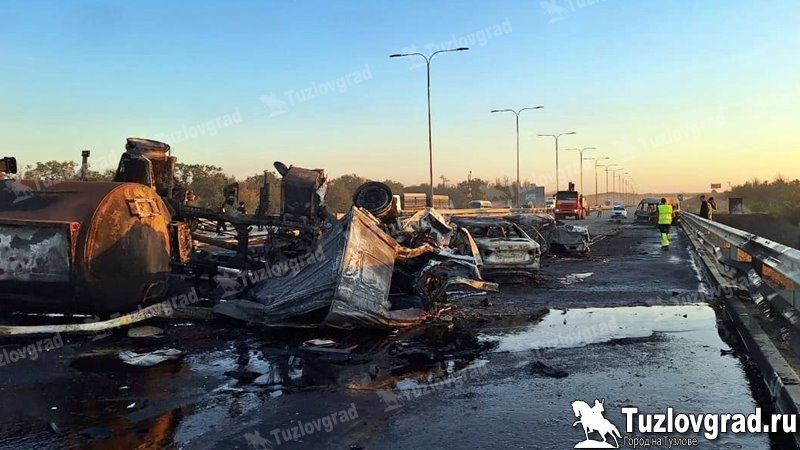 Стали известны подробности страшного ДТП на трассе М4 около аэропорта «Платов» - погибли 4 человека, 6 в больнице Весь траффик в сторону Москвы ГАИ перенаправляет через Новочеркасск. ДТП произошло на 1025 км трассы М4 29 июля около 01:30. По предварительной информации, водитель автоцистерны с битумом на базе «Мерседес Актрос» двигался по трассе в сторону Ростова, уснул за рулем, машина сместилась вправо, врезалась в отбойник справа от дороги, после чего опрокинулась и вылетела на сторону встречного движения, пробив центральное ограждение. На стороне встречного движения автоцистерна столкнулась с «Пежо Бокстер» и двумя легковыми автомобилями: «Фольксваген Пассат» и «Лада Веста». Также разлившийся из поврежденной цистерны битум воспламенился, и произошел сильный пожар. В результате ДТП погибли водитель «Мерседеса» неизвестно, скончался он от травм или сгорел , водитель и два пассажира один из них - несовершеннолетний автомобиля «Фольксваген». Еще 6 человек получили травмы различной степени тяжести и были доставлены в больницу города Шахты бригадами скорой помощи: водитель грузового фургона «Пежо», водитель «Весты» и четыре его пассажира среди них двое детей . На новочеркасской развязке трассы М4 дежурит экипаж ГАИ, который перенаправляет весь траффик трассы М4 в северном направлении через Новочеркасск, т.к. движение после развязки аэропорта полностью перекрыто. Там работают следственно-оперативная группа полиции, спасатели, Росавтодор.
