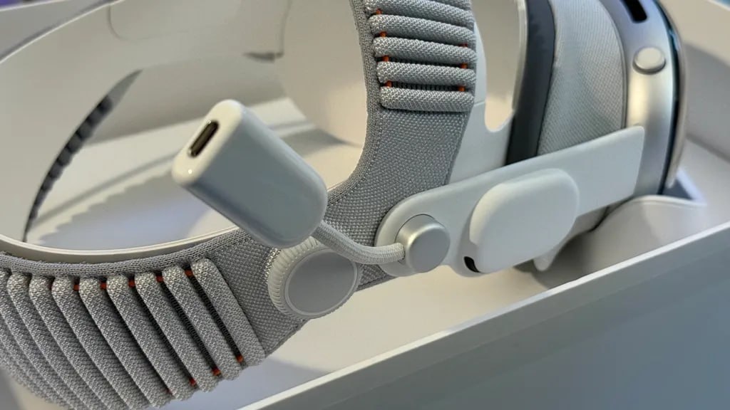 Apple выпустила Developer Strap аксессуар с USB C для Vision Pro за 300 Apple представила новый аксессуар для гарнитур Vision Pro добавляющий порт USB C к устройству Developer Strap совместим как с моделью M2 так и с M5 и предназначен для разработчиков создающих приложения под экосистему Apple Обычная Vision Pro не имеет разъёмов она питается от аккумулятора Developer Strap заменяет правую аудиоленту гарнитуры сохраняя звук и добавляя порт для высокоскоростной передачи данных Если прежняя версия ограничивалась USB 2 480 Мбит с то новый вариант поддерживает до 20 Гбит с быстрее чем у iPhone 17 Pro и большинства домашних сетей Apple отмечает что аксессуар ускоряет разработку графически нагруженных приложений и игр 3 0 0