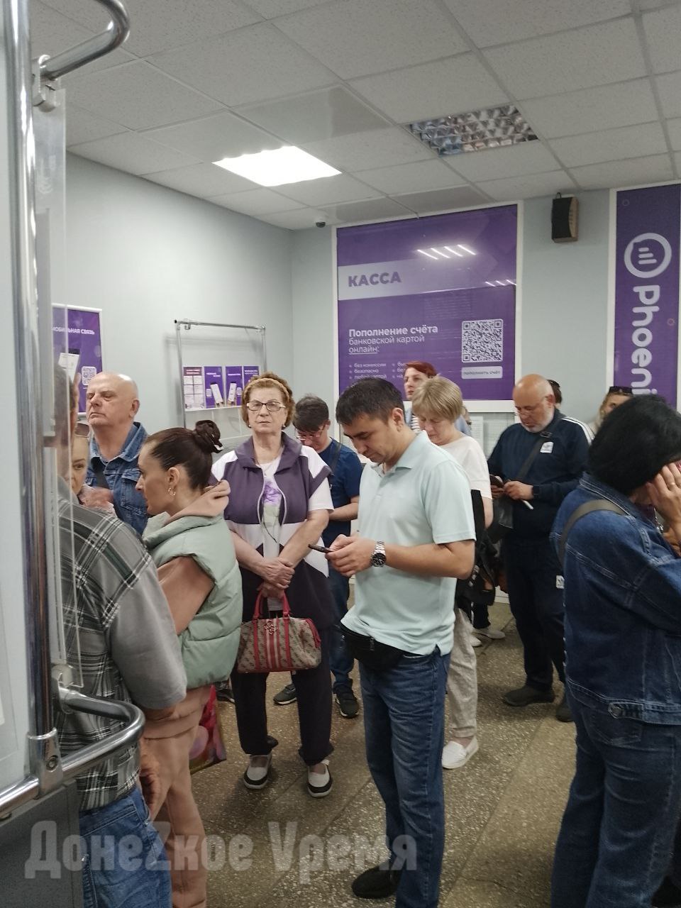 Ажиотаж не спадает: в очередях на переоформление сим-карт "Феникс" стоят сотни дончан Дата блокировки сим-карт "Феникс", чьи владельцы не подтвердили свои личные данные, все ближе. О переносе сроков с 1 июля на 1 ноября ранее говорили, но официальных сообщений так и не поступило. Абоненты боятся остаться без связи, поэтому спешат, образовывая длинные очереди. Подписчицы "Донецкого времени" Наталья и Любовь хотели пройти верификацию в офисе оператора в микрорайоне Текстильщик. В 07:30, то есть еще до открытия, им предложили 76-ю позицию в очереди. "В очереди было по спискам 75 человек. И там всего два окна. Люди пишутся с 4 утра", — написала в редакцию Наталья. Женщины решили попытать счастья в центральном офисе "Феникс" в районе Главпочтамта. Там к открытию уже образовались две очереди по 60-65 человек. "Одна очередь на переоформление сим-карт с паспортов Украины и ДНР на себя же, а вторая — на переоформление номера на другого человека", — объяснила Любовь. Она отметила, что в первой стоят и желающие купить новые стартовые пакеты. Люди негодуют, потому как больше купить сим-карты сейчас негде. В остальном атмосфера куда лучше, чем может показаться. Во-первых, людей, впускают в прохладное помещение, где есть стулья. А во-вторых, работают четыре окна, поэтому очередь продвигается довольно быстро. Наши подписчицы были 64-е и обслужили их примерно через два с половиной часа. Кроме коротких сроков и недоступности сим-карт осталась нерешенной и другая проблема. Наталья и Любовь стали свидетелями того, как в офисе "Феникс" отказали в верификации женщине, чья сим-карта оформлена на умершую мать. Предоставленное свидетельство о смерти никак не решило вопрос. Выходит, что до блокировки номеров осталось меньше двух недель, а обещанные механизмы в полной мере так и не заработали. Фото от подписчиков "Донецкого времени"