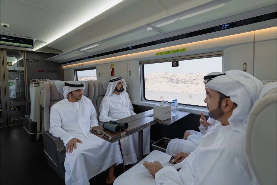Шейх Мохаммед совершил историческую поездку на поезде Etihad Rail    Вице-президент и премьер-министр ОАЭ шейх Мохаммед бен Рашид Аль Мактум совершил пробную поездку на пассажирском поезде из Дубая в Фуджейру, ознакомившись с ходом реализации национального железнодорожного проекта Etihad Rail. Это символическое событие предшествует запланированному на 2026 год запуску коммерческих пассажирских перевозок.    Во время поездки шейх Мохаммед подчеркнул стратегическое значение проекта, назвав его "жизненно важной экономической артерией", которая укрепит позиции ОАЭ как ведущего логистического центра. Пассажирские поезда смогут развивать скорость до 200 км/ч и перевозить до 400 пассажиров за рейс.    Проект предусматривает создание сети, соединяющей 11 городов и регионов страны. Первые четыре станции появятся в Абу-Даби, Дубае, Шардже и Фуджейре. Ожидается, что к 2030 году железная дорога будет обслуживать 36,5 млн пассажиров ежегодно.    Etihad Rail уже функционирует как грузовая сеть, а ее пассажирское направление станет важным шагом в реализации экологических целей ОАЭ, способствуя сокращению выбросов и транспортных заторов. Проект отражает стремление страны к созданию современной, устойчивой транспортной системы, объединяющей все эмираты.