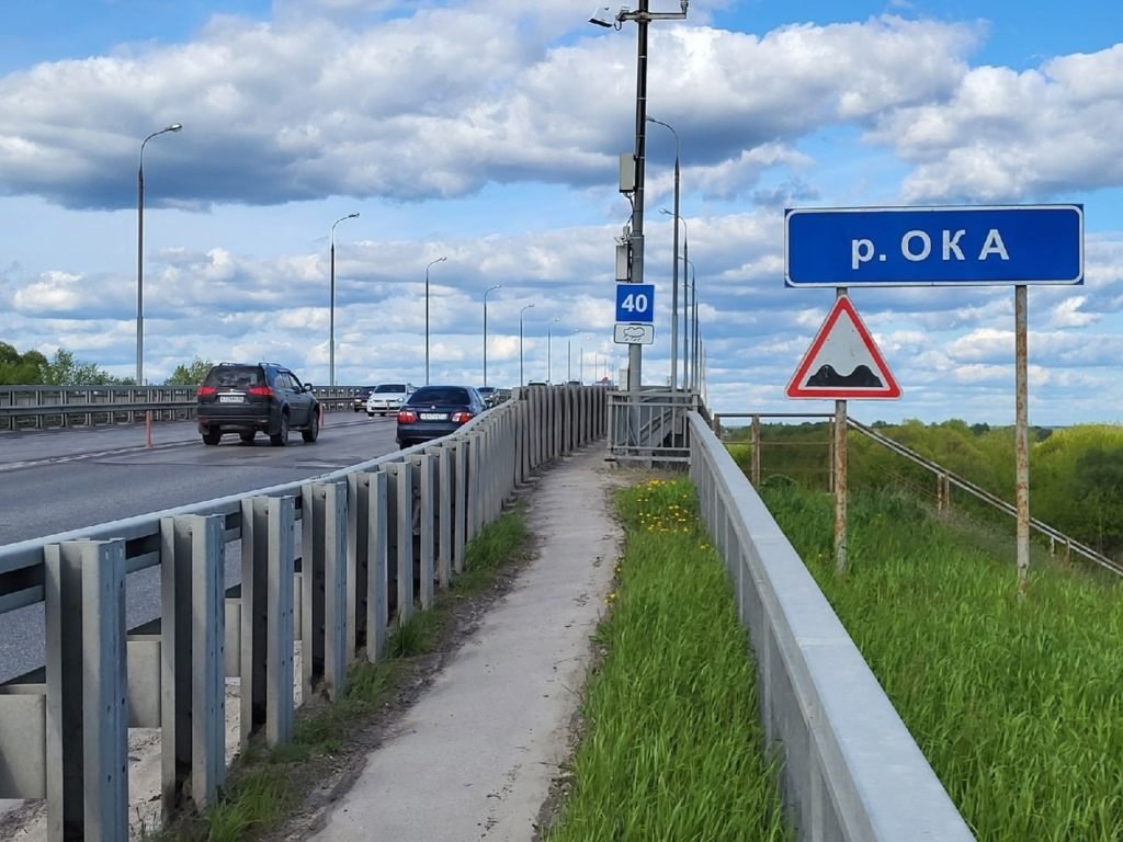 Состояние моста через Оку в Рязани оценят специалисты. Скорость движения по нему ограничена до 20 км/ч  В этом году по нацпроекту «Инфраструктура для жизни» стартовали работы по строительству нового моста через Оку. Строительство поддержал Президент России По поручению губернатора региона Павла Малкова к проектированию данного объекта протяженностью 5,8 км приступили в августе 2023 года. Мостовое сооружение будет примыкать к региональной сети автомобильных дорог. Съезды с развязки будут вести с одной стороны к трассе Шереметьево – Дядьково – Вышгород – Наумово – Гавердово, с другой – к дороге Рязань  от села Шумашь  – Спасск-Рязанский – Ижевское – Лакаш.  Как сообщается на сайте минтранса Рязанской области, новый мост не только улучшит транспортную инфраструктуру региона, но и соединит между собой областной центр, поселок Солотча и пять муниципальных образований Рязанской области, а также обеспечит надежную связь с Владимиром и Нижним Новгородом.  Существующий мост через реку Ока, расположенный на Соло...