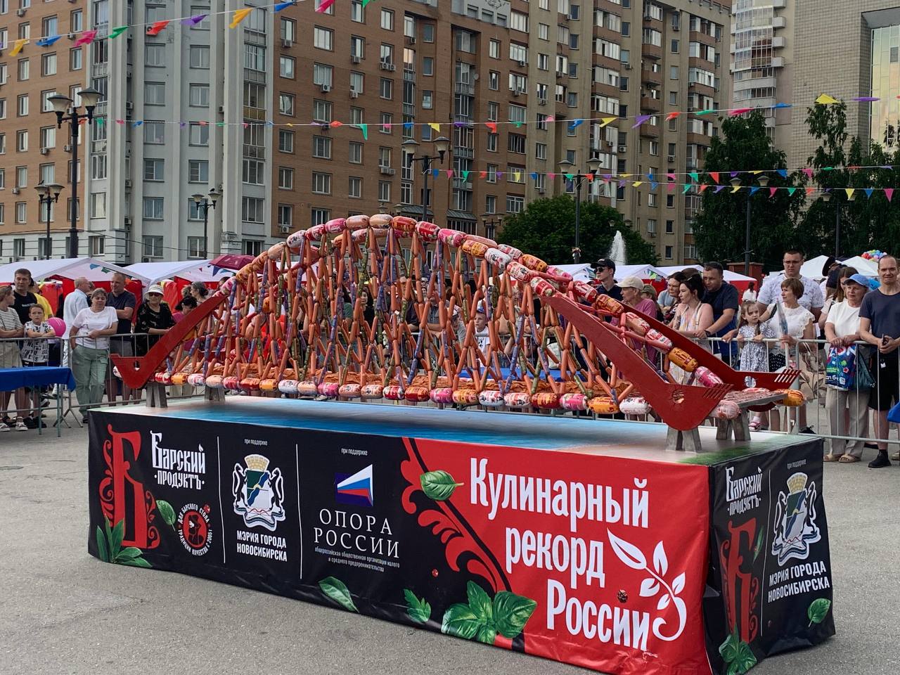 В честь Дня города в Новосибирске появился Бугринский мост из колбасы  Гастрономический рекорд в виде арт-объекта из колбасных изделий представил новосибирский производитель — компания ООО «Барский продукт» на выставке местных товаропроизводителей, которая проходит сегодня на площади Пименова.   Афиша Новосибирска
