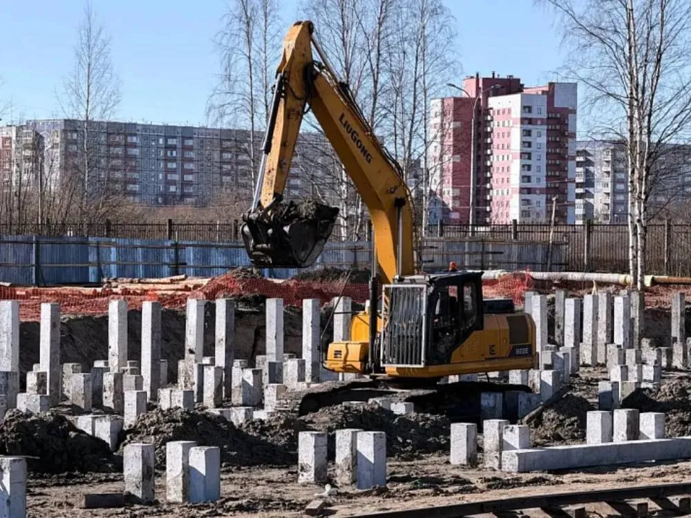 Строительство бассейна на стадионе Север в Северодвинске идёт с опережением графика Трехэтажный спортивный комплекс площадью порядка 10 тысяч квадратных метров будет включать две бассейные чаши и два просторных спортивных зала Основная чаша размером 53 на 25 метров позволит проводить соревнования до межрегионального уровня вторая 9 6 на 5 6 метра предназначена для занятий дошкольников и оздоровительного плавания В здании разместятся раздевалки зрительские трибуны медицинский кабинет с зоной для допинг контроля буфет гардероб и другие помещения Реализация проекта осуществляется по схеме под ключ генеральный подрядчик отвечает за все этапы от проектирования и строительства до комплексного оснащения технологическим и спортивным оборудованием Финансирование удалось привлечь благодаря соглашению между Министерством спорта РФ и правительством Архангельской области регион получил субсидию на создание и модернизацию объектов спортивной инфраструктуры Общий бюджет проекта превышает два миллиарда рублей а завершить строительство планируется до конца 2027 года В настоящее время подрядная организация ведет подготовительные работы и устройство свайного поля с опережением графика из 1109 запланированных свай уже погружено 506 что значительно превышает плановые показатели Фото пресс службы губернатора и правительства