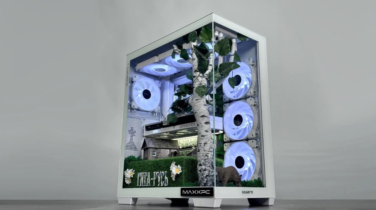 В России представили кастомный игровой ПК ГИГА РУСЬ с березкой внутри Российский сборщик кастомных компьютеров MaxxPC совместно с компанией GIGABYTE анонсировали игровой ПК под названием ГИГА РУСЬ Выпуск системы приурочен ко Дню народного единства Корпус компьютера расписан узорами в стиле гжель За прозрачной боковой панелью находится декоративная композиция включающая миниатюрную избушку с колодцем и пластиковую березу Внутреннее убранство подсвечивается кулерами В основе сборки лежит материнская плата B850 AORUS STEALTH ICE За производительность отвечает процессор Ryzen 7800X3D и видеокарта RTX 5060Ti с 16 ГБ видеопамяти Также система оснащена 32 ГБ оперативной памяти стандарта DDR5 с частотой 6400 МГц и твердотельным накопителем объемом 1 ТБ Создатели утверждают что на данной конфигурации игра Смута работает на максимальных настройках графики Компьютер ГИГА РУСЬ был изготовлен в единственном экземпляре и не предназначен для продажи
