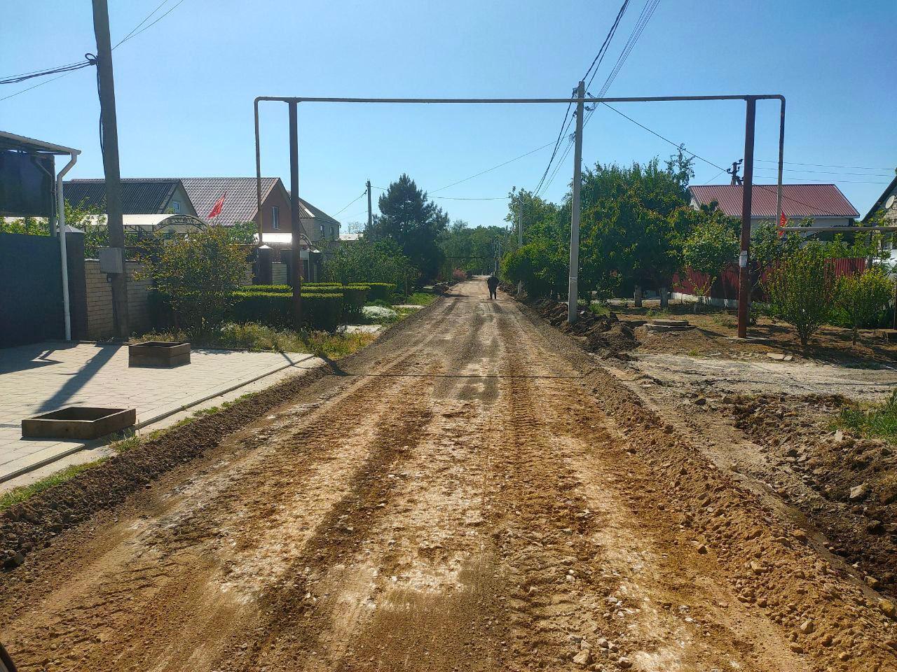 В сельских округах Анапы продолжается ремонт дорог и обустройство тротуаров В Гостагаевской на улицах Крымской и Кубанской ведутся работы по укладке нового асфальта, капитальному ремонту покрытия и укреплению дорожного полотна. На Цветочной и Южной — отсыпка фрезерованным асфальтобетоном. Уже отсыпаны щебнем улицы Механизаторов, Лермонтова, Трудящихся, Казачий и Солнечная. На улице Мира расширяется проезжая часть до 7 метров, обустраиваются новые тротуары. В Джигинке асфальтируется переулок Северный протяжённостью около километра. Основание уже отсыпано, выполнено грейдирование и уложен первый слой асфальта. Также строится безопасный пешеходный тротуар. В Виноградном ремонт идёт на улице Ореховой — она соединяет микрорайон новостроек с федеральной трассой. Рабочие укладывают основание и готовят участок от улицы Вишнёвой до Таманской к асфальтировке. Ширина полотна составит 6 метров — дорога обеспечит удобный выезд для жителей и строящихся домов. В Анапской выполняются работы по отсыпке фрезерованным асфальтобетоном: улица Лермонтова — от улицы Мира до улицы Набережной, улица Советская — от улицы Мира до улицы Набережной. Также запланирован капитальный ремонт улицы Черноморской — от Солнечной до Суворова. Дорожный сезон в разгаре: работы идут в разных округах параллельно, охватывая как центральные улицы, так и локальные проезды.