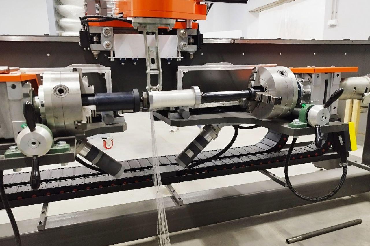 Донские учёные создали уникальный станок для производства композитных материалов В Новочеркасском политехе по заказу кировского завода Маяк входит в концерн Калашников разработали и построили роботизированную систему которая создаёт детали выполненные методом намотки Новое оборудование позволит предприятию стать независимым от внешних поставщиков наладив самостоятельный выпуск деталей выдерживающих нагрев до 300 C Каждая нить стекловолокна проходит через ванну с жидкой смолой пропитывается ею а затем наматывается на вращающуюся оправку по заранее заданной схеме Рисунок создается в специальной программе Затем намотанные волокна уплотняются для удаления излишков смолы далее полученная структура отвердевает волокна становятся частью детали По своим техническим характеристикам комплекс превосходит зарубежные аналоги Он поставляется вместе со специальным программным обеспечением также созданным в институте