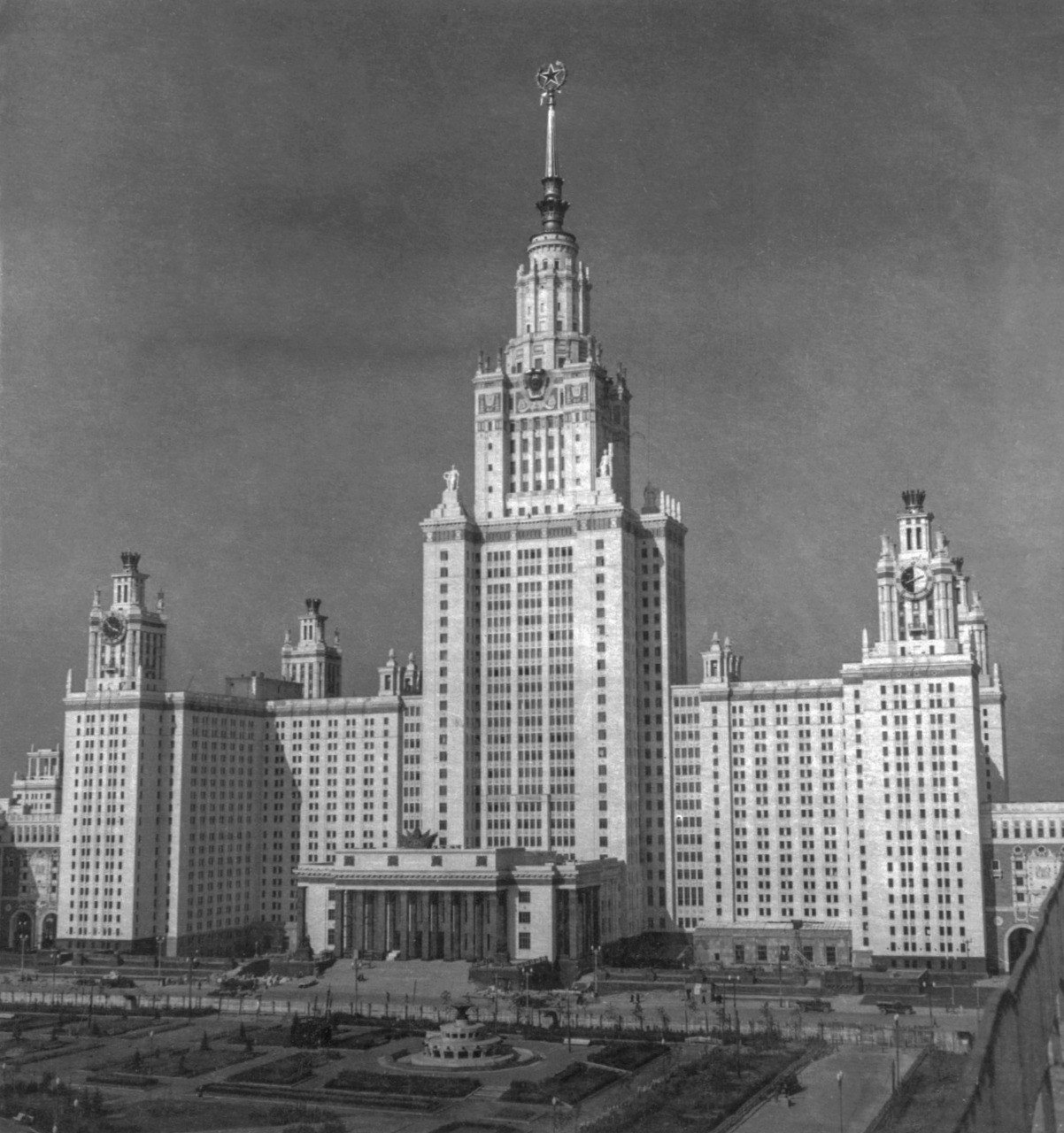 1 сентября 1953 года открылось высотное здание МГУ на Ленинских горах Современников оно поражало масштабами и роскошью интерьеров студентов главного вуза страны окружали мраморные лестницы гранитные колонны мозаики и скульптуры Конструктивные особенности здания тоже впечатляли его фундамент уходил в глубину на 12 14 метров а каркас состоял из 40 тысяч тонн стали Высота центрального корпуса составляла 235 метров на протяжении полувека университет оставался самым высоким зданием не только в столице но и во всей стране Любопытные факты о создании знаменитой высотки вы найдете в фотоальбомах Строительство МГУ на Ленинских Воробьевых горах представленных в виртуальном музее Москва с заботой об истории Здание Московского государственного университета им М В Ломоносова на Ленинских горах Автор В Носков Москва сентябрь 1953 г Главархив Москвы Главархив Москвы