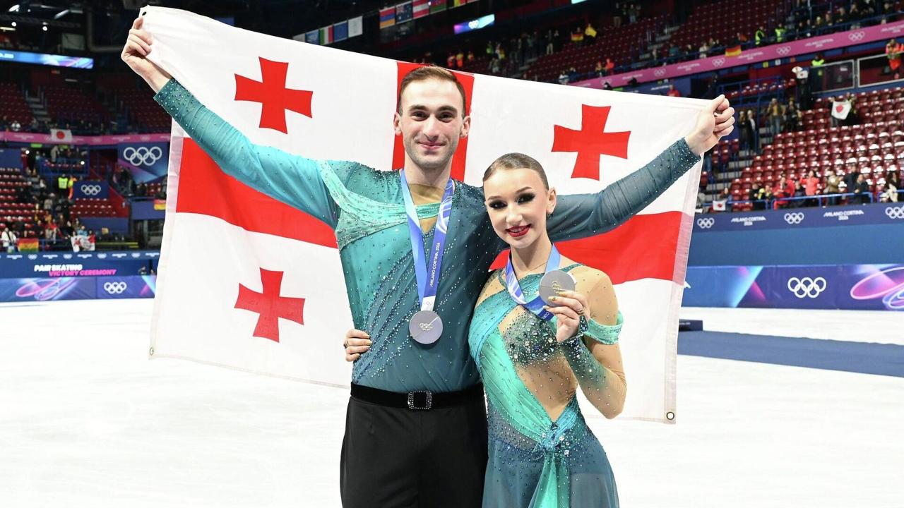 Грузия впервые в истории завоевала медаль на зимних Олимпийских играх Историческое серебро стране принесли фигуристы Анастасия Метёлкина и Лука Берулава в соревнованиях спортивных пар По итогам короткой и произвольной программ дуэт набрал 221 75 балла и занял второе место уступив только паре из Японии 231 24 Метёлкиной 20 лет Берулава 23 Это один из самых ярких дуэтов последних лет в их активе золото чемпионата Европы 2026 года а также серебро 2024 и бронза 2025 этого турнира Оба спортсмена родились в России Анастасия во Владимире Лука в Москве Метёлкина начала карьеру в 2009 году выступая в парном катании за российскую сборную с разными партнёрами Берулава встал на коньки в три года тренировался в Москве а в парное катание пришёл под руководством Нины Мозер Позже продолжил подготовку в Перми у Павла Слюсаренко Tbilisi Long Stay в Телеграм Инстаграм ТикТок