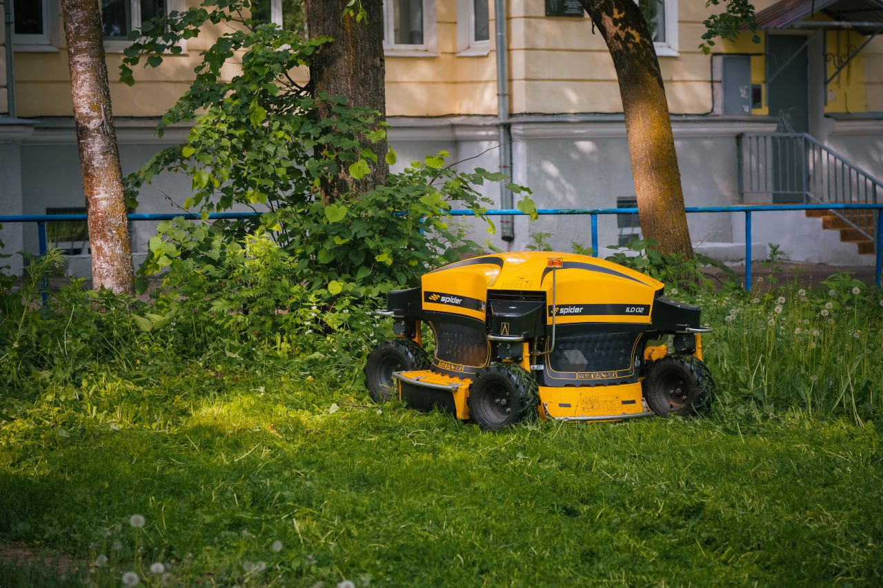 Администрация Сергиево-Посадского городского округа привлекла для скоса травы робота-газонокосильщика Этот аппарат ранее использовался на рекультивированном полигоне в Парфёново – он окашивал склоны. Теперь его планируют использовать для скоса травы в населённых пунктах округа. Поле для эксплуатации есть. «Она очень хорошо работает. Сейчас мы тестируем её, чтобы освободить рабочие руки и задействовать людей в других рабочих моментах. В данном случае, когда ею управляет оператор — а я с ней вполне хорошо справляюсь — машинка управляется с пульта, колёса работают на 360 градусов, нож опускается электрически на нужную высоту. Вот и всё для полноценной работы», — рассказывает оператор робота Евгений Шваров. Говорить о полной автономности не приходится. Робот зависит от человека, который управляет им и доставляет к месту работы. Кстати, весит он около 400 килограммов. Такую тяжёлую газонокосилку привозят на специальной технике или эвакуаторе. Да и доделывать за ним тоже иногда нужно. Впрочем, кроме этого минуса есть и плюсы. «В принципе, по временному отрезку она выполняет намного быстрее. Если мы возьмем, допустим, 3-4 сотрудника с триммерами, то эта машинка на 75% быстрее выполнит ту работу, чем те сотрудники, которые будут косить триммера. Поэтому считаю, что данная техника целесообразна для покоса больших площадей», — считает Евгений Николаевич. Кстати, водители могли видеть подобные аппараты на федеральных автотрассах. Робот ездит по склону, а оператор управляет им с обочины. Занимательное зрелище. Не исключено, что жители Сергиева Посада увидят этот процесс в ближайшее время.