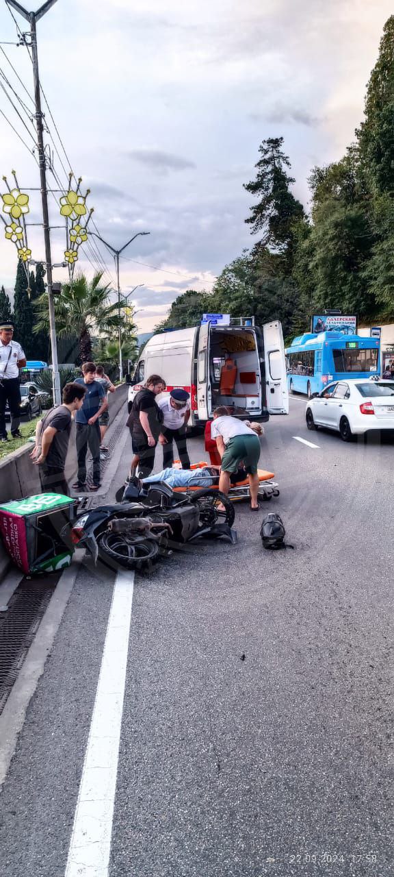 В Адлере мопедист попал под машину после того, как влетел в дорожную яму  По словам очевидцев, курьер на мопеде двигался по улице Ленина, когда попал неожиданно попал передним колесом в яму на дороге. Он не смог удержать свой транспорт, упал и оказался под колесами попутной машины.   Пострадавшего с различными травмами госпитализировали.