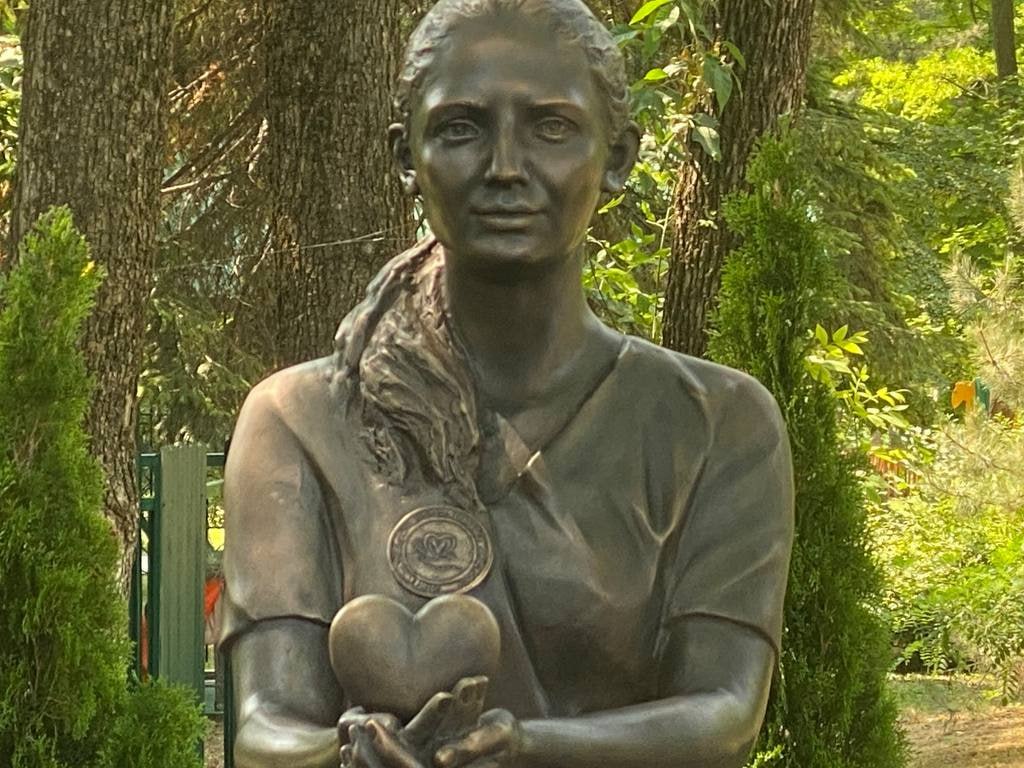 Первый в России памятник волонтерам СВО открыли в Ростове-на-Дону В Ростове-на-Дону, в парке имени Октября открыли первый в России памятник волонтерам СВО. Только из донского региона с начала 2022 года в зону СВО, Курскую и Белгородскую области отправили 25 тысяч тонн гуманитарной помощи. После начала Специальной военной операции количество волонтеров в стране увеличилось на 30%. «Это те люди, которые ежедневно приближают нашу победу, но дело в том, что до сих пор и в России, и в мире памятника волонтеру СВО не было, – рассказал один из инициаторов установки, депутат ростовской Гордумы Вячеслав Лобырев. – Так в прошлом году возникла эта идея. К созданию памятника привлекли одного из лучших в стране ростовского скульптора Дмитрия Лындина». Сердце, которое девушка держит в ладонях, обращено в сторону окружного военного госпиталя, расположенного неподалёку. Там работает Ксения Левенцова – прототип памятника. Вместе с другими волонтерами и врачами она ставит раненых бойцов на ноги. Южная служба новостей