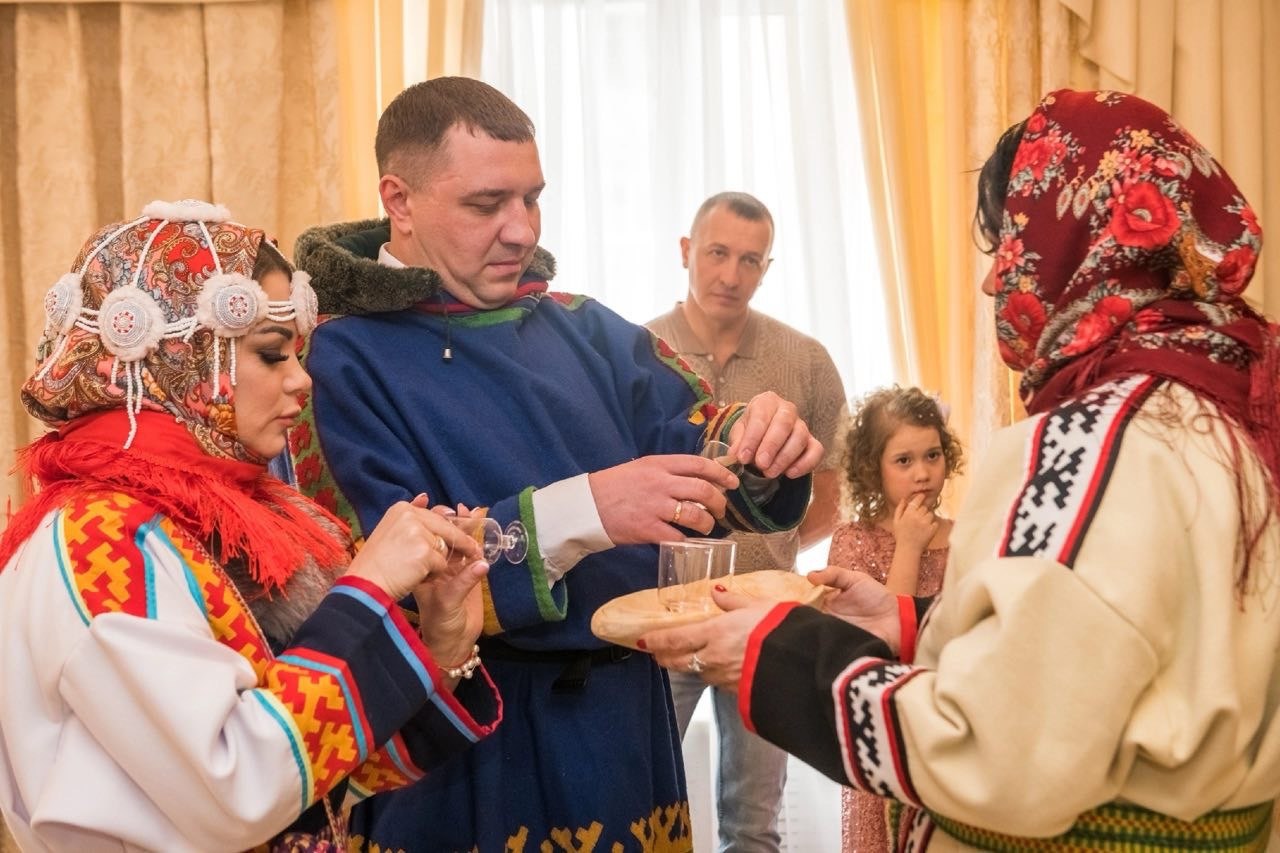 На Севере Красноярского края состоялась первая этническая свадьба в рамках «Национальные свадьбы Сибири». Сначала молодые официально зарегистрировали свой брак в стенах ЗАГСа. А уже затем стали участниками церемонии, основанной на традициях коренных народов Севера. Были тут и звуки бубна, и очищение дымом от ветки багульника, и обереги из бивня. Следуя эвенкийскому обычаю, невеста угостила огонь и прикурила для жениха трубку из бивня мамонта, символически присоединившись к его роду. Жених символически «забил оленя». Вместе собрали чум. И под конец – танец хейро вокруг священного дерева, к которому повязали цветные ленточки с желаниями. : Наталья Сидорова, krskstate.ru