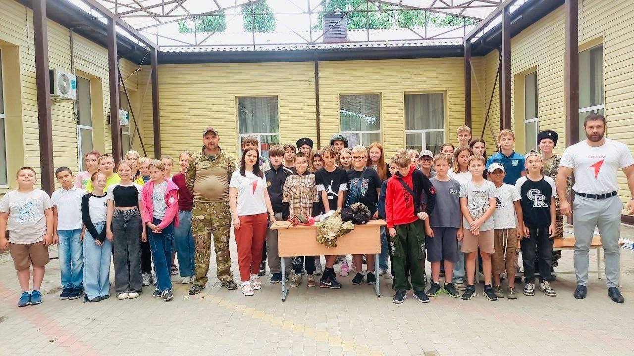 Школьникам о важном В летнем лагере школы № 44 станицы Северской провели занятия с детьми. В гости к ученикам пришел ветеран боевых действий, участник спецоперации, председатель муниципального отделения Союза казачьей молодежи Кубани Виталий Ничик совместно с воспитанниками казачьего военно-патриотического клуба «Восход». В ходе встречи школьники смогли примерить солдатское снаряжение и освоить базовые навыки оказания первой доврачебной помощи под руководством опытных наставников. Мероприятия с казаками помогают укрепить чувство патриотизма у подрастающего поколения и сохранить связь между поколениями, передавая важные знания.