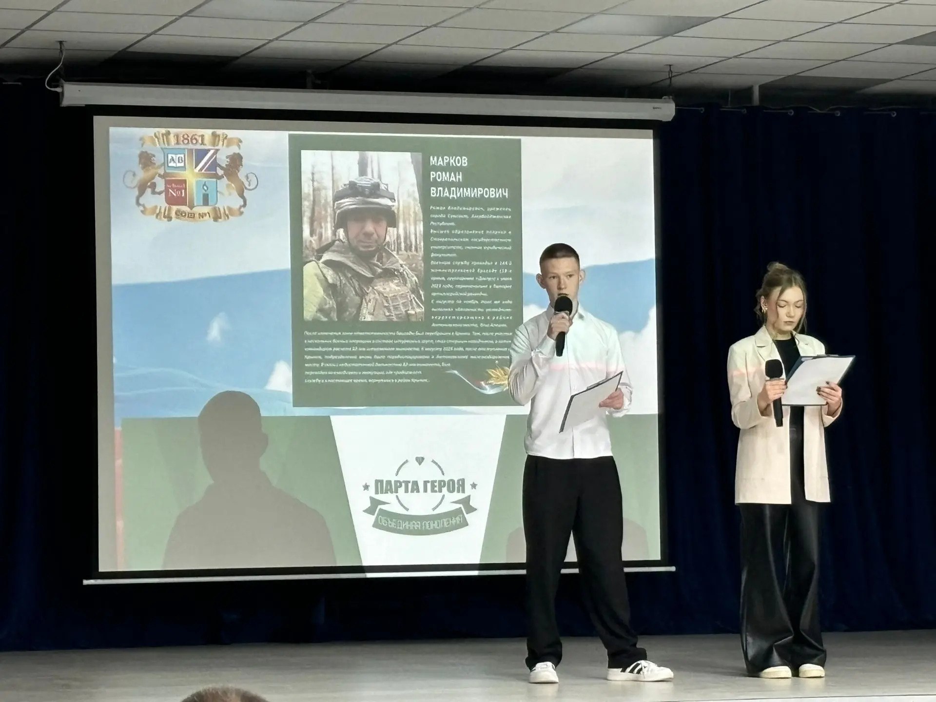 Парту Героя открыли в школе 1 Ставрополя в преддверии Дня защитника Отечества Она посвящена участнику СВО Роману Маркову награжденному медалью Суворова Роман с июня 2023 года выполняет боевые задачи Под Херсоном его работа помогла уничтожить вражескую артиллерию в Крынках он командовал расчетом штурмового миномета В 2024 году получил ранение но после восстановления вернулся в строй Герой многодетный отец двое его детей уже окончили эту школу младшая дочь учится здесь в третьем классе Право сидеть за Партой Героя получат лучшие ученики Ставрополь в MAX