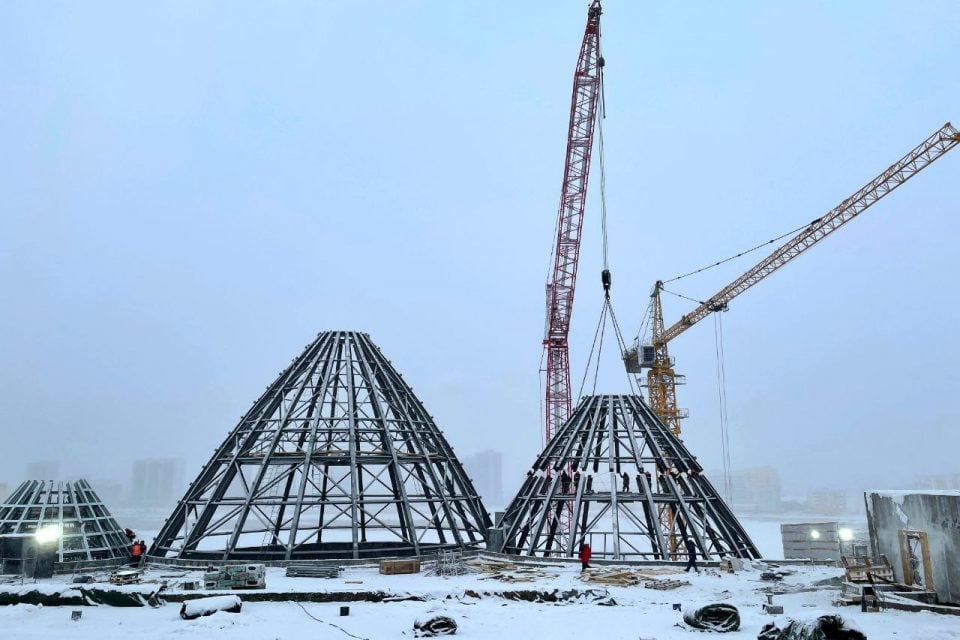 На крыше Арктического центра в Якутске успешно завершили установку металлических куполов    Закончился монтаж металлической конструкции третьей урасы на крыше нового Арктического центра в Якутске.   Таким образом, каркас здания теперь полностью готов и включает три урасы, а также светопрозрачный купол, напоминающий озеро, расположенный на вершине.  Новости Якутия  Благоустройство