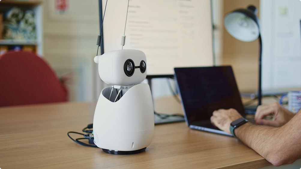 Hugging Face запилили настольного программируемого робота Reachy Mini. Идея в том, что он маленький, опенсорсный и его сможет позволить себе каждый, так как он стоит всего 300 долларов. Полагаю так дешево, поскольку у него нет рта и груди, только голова с глазами и антенны. У конкурентов робобюсты со ртом и грудью стоят от $20 000, а с ногами и телом под $175 000. Но без антенн, правда.