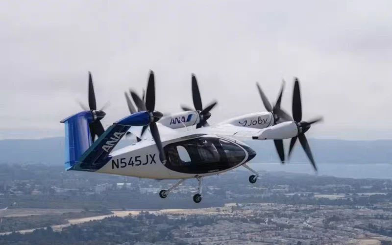 Joby Aviation демонстрирует аэротакси в Японии Компания Joby Aviation провела демонстрационный полет своего электрического аэротакси с вертикальным взлетом и посадкой eVTOL на выставке Expo 2025 в Осаке Это первый в истории полет подобного аппарата на всемирной выставке организованный совместно с авиакомпанией ANA Этот шаг часть плана по созданию в Японии национальной сети воздушных такси Проект начнется в Токио и предполагает развертывание более 100 аппаратов а также строительство вертипортов и организацию программ обучения пилотов Публичные полеты призваны познакомить людей с новой технологией и собрать данные для сотрудничества с авиационными властями Японии После сертификации аэротакси Joby S4 сможет перевозить пилота и четырех пассажиров со скоростью до 320 км ч Аэротетраэдр eVTOL