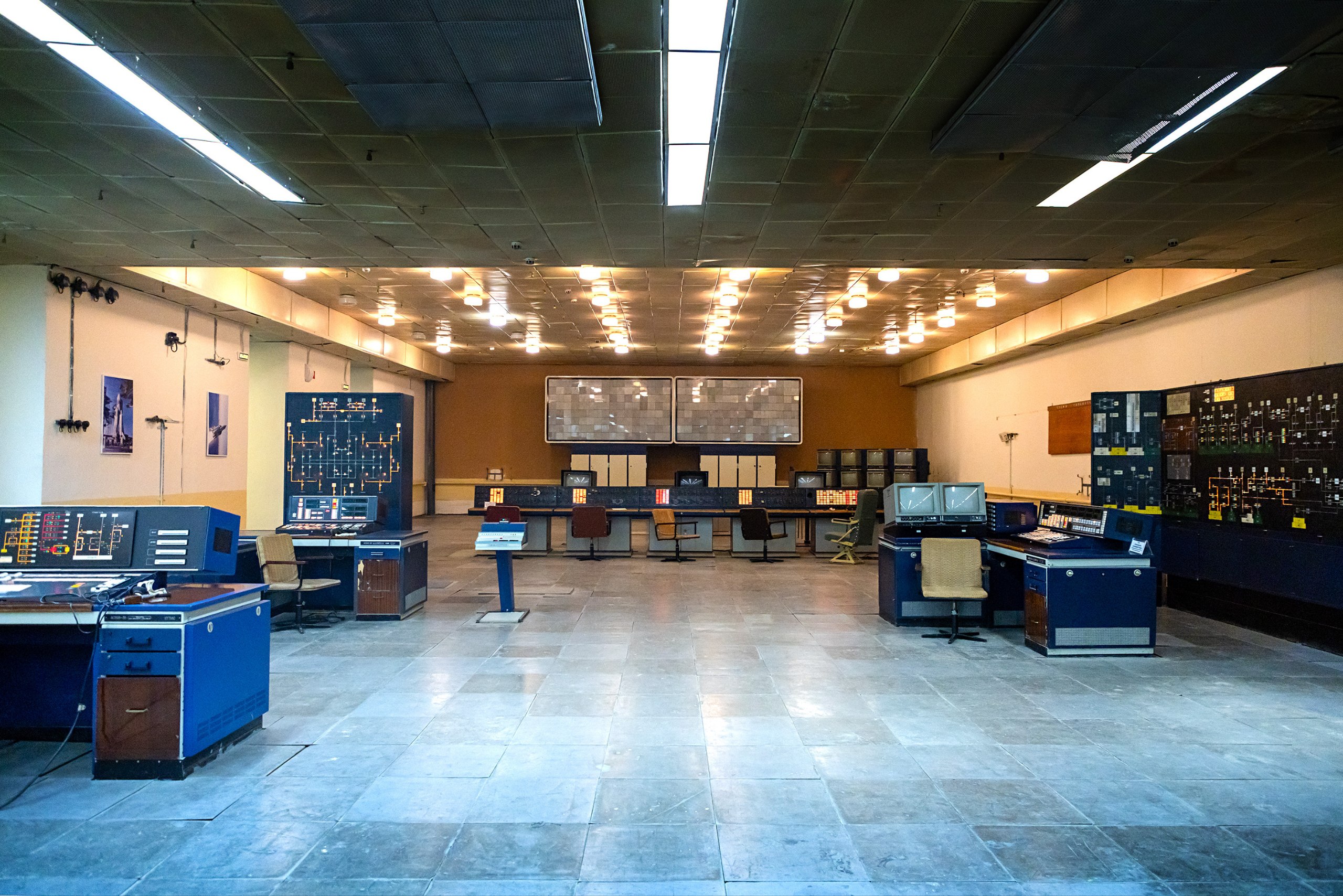 Отправляемся на легендарную площадку 250а Здесь расположен командный центр управления космическим кораблем Буран Одно из самых атмосферных мест Байконура по мнению наших туристов Атмосфера напоминает произведения советских фантастов Заглубленные для безопасности помещения монументальные двери шлюзы способные наглухо перерезать центр в случае необходимости Огромные залы с пультами управления и мягкий свет потолочных светильников Таблички и плакаты на стенах переносят в прошлое когда здесь звучала лебединая песня советской космонавтики Энергия Буран Система внутренней громкой связи прекрасно работает можно даже сесть в кресло и отдать пару команд на пуск ракеты Читайте серию постов о программе Энергия Буран