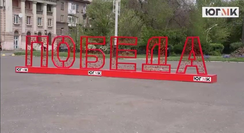 При поддержке ЮГМК на площади Ленина в Алчевске установлена специальная масштабная конструкция со словом «Победа» Любой житель и гость Алчевска может завязать на ней георгиевскую ленточку, тем самым отдать дань памяти героям, погибшим в Великой Отечественной войне, рассказал гендиректор управляющей компании Южного горно-металлургического комплекса «Союзметаллсервис» Валерий Шерин, сообщает пресс-служба ЮГМК. В рамках рабочего визита в ЛНР Валерий Шерин также посетил Алчевский коллегиум № 1 имени Христины Алчевской. От ЮГМК библиотечному фонду коллегиума были переданы экземпляры детской книги «Между двух огней», посвященной истории Великой Отечественной войны. Также в алчевском сквере Доблести и Славы состоялась акция по посадке именной яблоневой аллеи «80-летие Победы», организованной ЮГМК и администрацией городского округа. Совместными усилиями участники акции посадили 50 молодых яблонь.