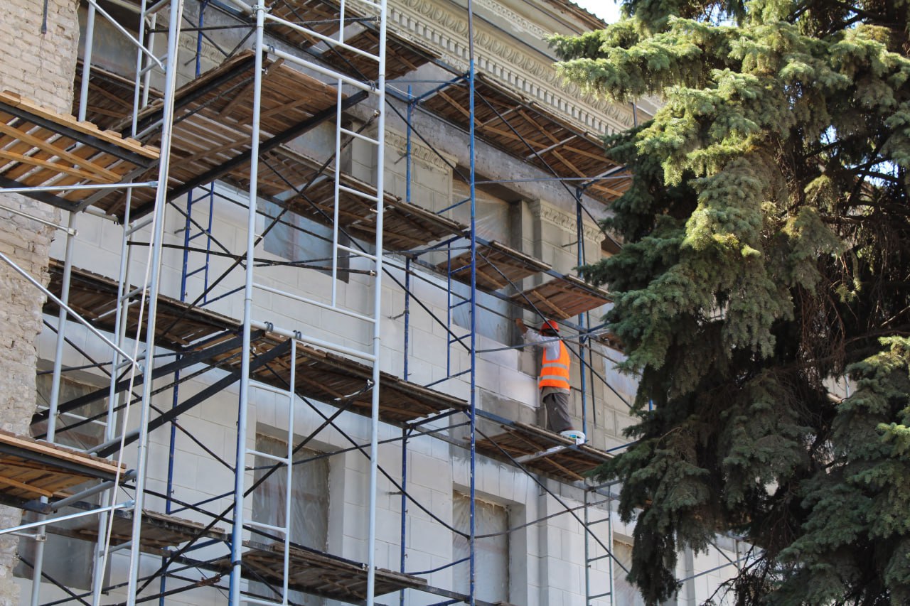 В рамках специального инфраструктурного проекта в Краснодоне продолжаются масштабные работы по капитальному ремонту фасада Дворца культуры имени «Молодой гвардии». На сегодняшний день демонтаж старой штукатурки выполнен уже на 95%. На отдельных участках фасада специалисты приступили к нанесению новой штукатурки и восстановлению декоративных узоров. Особое внимание уделяется деталям: элементы декора восстанавливают вручную, тщательно повторяя оригинальные формы, чтобы сохранить исторический облик здания. Ведется подготовка к установке новых барельефов на фронтоне: их изготовление осуществляется по современным технологиям с использованием 3D-моделирования в г. Ростове-на-Дону. Уже в середине августа мастерами будет проведена кропотливая работа по монтажу этих уникальных элементов. Несмотря на сложные погодные условия, работы идут с опережением графика. Обновленный фасад Дворца культуры станет настоящим украшением города и символом бережного отношения к культурному наследию. Сергей Козенко