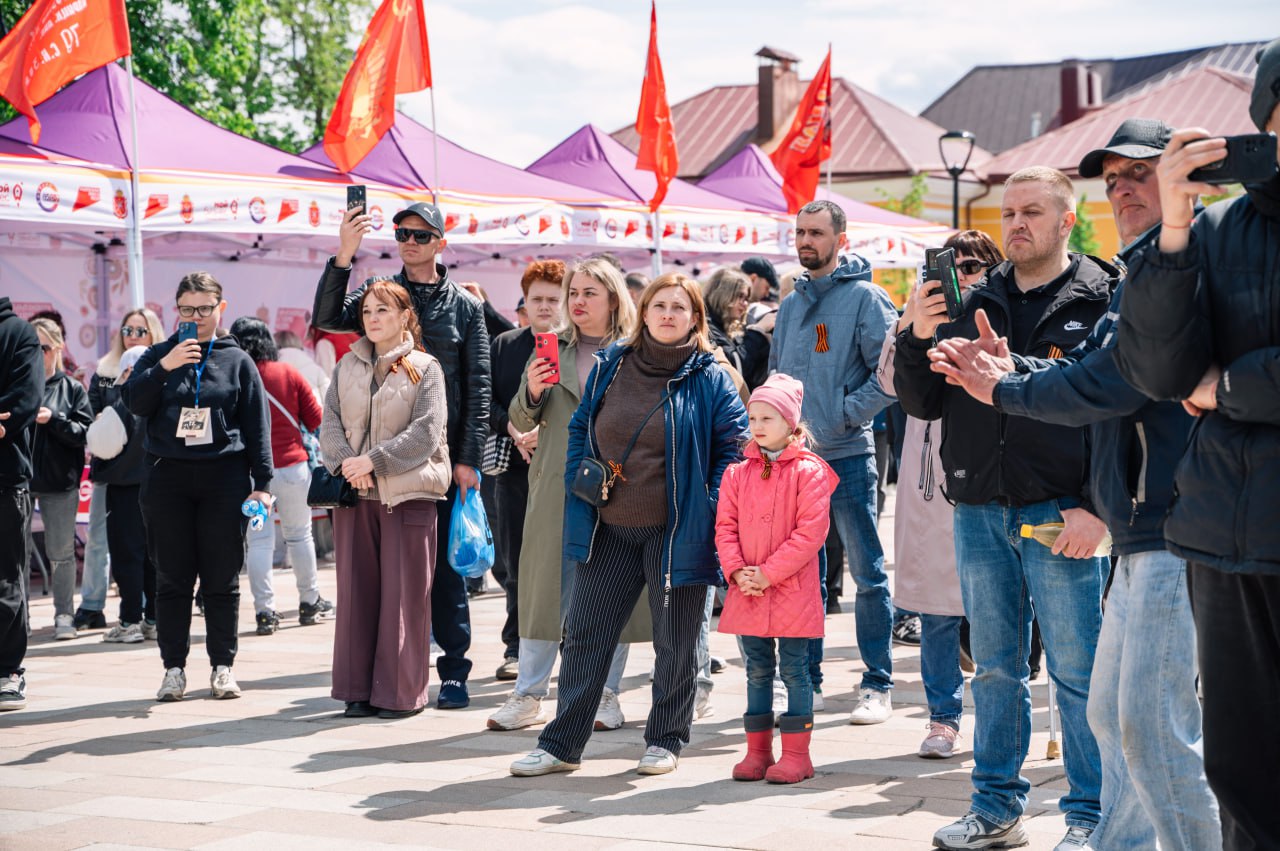 На стенде Национального центра «Россия» в Туле отметили День Победы 9 мая в историческом центре Тулы на стенде Национального центра «Россия» прошли мероприятия, посвящённые 80-летию Великой Победы. Их подготовили министерство развития предпринимательства и торговли региона и Центр «Мой бизнес». Программа началась с праздничного концерта «Никто не забыт, ничто не забыто». В нем приняли участие тульские исполнители Иван Рябинкин, Михаил Гришин, Игорь Каменских, Елена Добрякова, фольклорный ансамбль «Услада», коллектив «Непоседы» и группа ЖARA, школьники и студенты. В течение всего дня работала выставка детских рисунков и военно-полевая почта. Здесь гости и жители города писали письма нашим бойцам в зону проведения спецоперации. А в Универмаге тульских брендов прошел мастер-класс для детей участников СВО. На ярмарке региональные товаропроизводители, в их числе участники проекта «Сделано в Тульской области», представили свою продукцию. Гости праздника угостились настоящей солдатской кашей и отведали горячего чая из тульского 45-литрового самовара в стиле филимоновской игрушки. Завершилась программа акцией «Георгиевская лента». Тульские предприниматели, жители и гости областного центра в память о героях Великой Отечественной войны в Музейном квартале растянули десятиметровое полотно Георгиевской ленты и отпустили в небо белые шары. Память павших героев Великой Отечественной войны и специальной военной операции почтили минутой молчания.