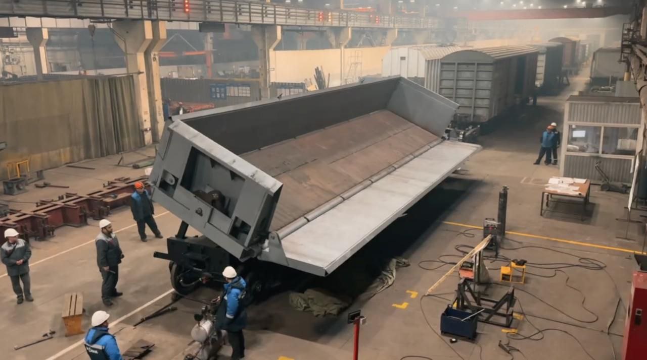 РМ Рейл Абаканвагонмаш запускает серийное производство инновационных вагонов самосвалов Компания РМ Рейл Абаканвагонмаш приступает к серийному выпуску инновационных вагонов самосвалов собственной разработки Данная модель предназначенная для транспортировки скальных пород и руды в условиях горнорудных карьеров представляет собой одну из новейших разработок предприятия Применение передовых конструктивных решений позволило обеспечить вагону уникальные технические и эксплуатационные характеристики не имеющие аналогов на российском рынке Для производства данной технически сложной продукции РМ Рейл Абаканвагонмаш обладает всей необходимой производственно технологической базой Трансфер ключевых технологий и компетенций в рамках межрегиональной кооперации обеспечивает компания Рузхиммаш В этих целях была организована мобильная система обучения сотрудники предприятия Абаканвагонмаш проходят двухнедельные стажировки на площадке Рузхиммаша где под руководством опытных наставников осваивают ключевые производственные операции На текущий момент в Абакане уже изготовлен опытный образец 6 осного думпкара повышенной грузоподъемности Вагон успешно прошел комплекс необходимых испытаний включая функциональное опрокидывание кузова с имитацией разгрузки на обе стороны Также на предприятии освоен выпуск специализированных труб пневморазгрузки используемых в производстве думпкаров Особое внимание уделяется вовлеченности персонала в новые процессы при этом качество выпускаемой продукции и соблюдение технологической дисциплины являются приоритетными задачами Параллельно с подготовкой к серийному выпуску на предприятии освоена сборка трехосной тележки модели 18 1245 В настоящее время на производственной площадке в активной фазе проводится техническое перевооружение нацеленное на организацию серийного выпуска думпкаров осуществляется закупка необходимого оборудования изготовление стапелей и оснастки а также формирование производственных потоков Старт серийного производства запланирован на январь 2026 года Фото из видеоматериала РМ Рейл