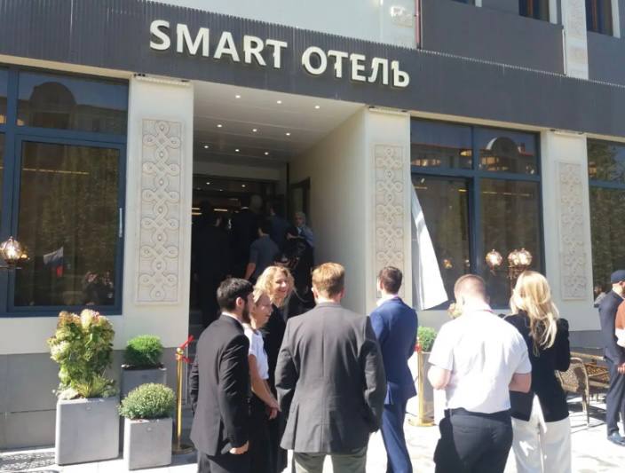 Открытие современного Smart Отеля состоялось в столице Ингушетии  В рамках празднования 100-летия ингушской государственности, в Магасе состоялось торжественное открытие нового Smart Отеля, который станет частью образовательного ИТ-кластера, сообщил корреспондент газеты «Ингушетия» с места события.  Smart Отель — это часть образовательного кластера, в который входят «Академия цифрового развития», «Школа 21» и «Бизнес-акселератор Ингушетии». Проект реализован группой «Сафмар» и ее основателем, предпринимателем и меценатом Микаилом Гуцериевым, при поддержке правительства республики. Теперь все желающие могут получить знания и начать карьеру в ИТ в бесплатной школе цифровых технологий «Школа 21», открытой на базе «Академии цифрового развития».  Во время прохождения отборочных «бассейнов», интенсивов и экзаменов участники «Школы 21» из других регионов СКФО смогут останавливаться в Smart Отеле бесплатно.  Он предлагает 42 современных одноместных и двухместных номера и кампус-студии, оборудованные телевизорами и специализированным программным обеспечением для командных игр. Для комфортного отдыха и продуктивной учёбы предусмотрена студенческая гостиная.  На первом этаже отеля открылся современный ресторан с разнообразным меню. Пространство ресторана предназначено для проведения неформальных встреч, рабочих обсуждений и отдыха. Удобная планировка и спокойная атмосфера делают его идеальным местом для гостей и жителей региона.   ПОДПИСАТЬСЯ  ПРЕДЛОЖИТЬ НОВОСТЬ