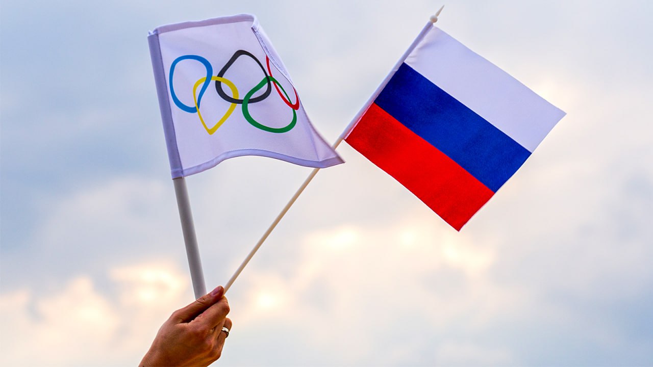 МОК запретил использование российских флагов и других символов на трибунах во время Олимпиады 2026 Такое правило было принято после инцидента на Тур де Ски когда болельщики размахивали российскими флагами во время церемонии награждения после того как российский лыжник Савелий Коростелев занял 4 е место в масс старте Radiosporten