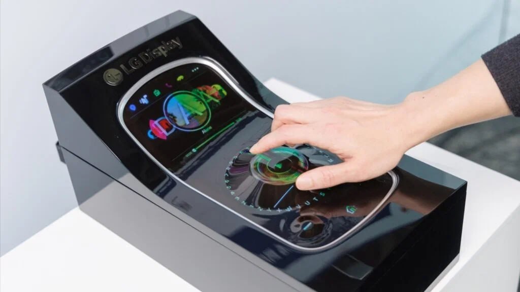 Компания LG показала растягивающийся и гнущийся автомобильный дисплей Каким образом реализована возможность увеличения площади дисплея, в LG не поясняют, но уточняют, что при растягивании он сохраняет и высокое разрешение, и цветопередачу. Опытный прототип экрана может увеличивать собственную диагональ в диапазоне от 12 до 18 дюймов. Также благодаря гибкости новинку можно разместить на поверхности практически любой кривизны. Кроме того, такой дисплей способен формировать выпуклые элементы управления: они поднимаются непосредственно из экрана. Ещё LG готовит ультраширокий 57 дюймов экран для передних панелей. Его предлагается устанавливать между стойками лобового стекла. Дисплей оборудован технологией, которая делает невидимой для водителя пассажирскую зону: тем самым пассажир может просматривать контент во время движения, не отвлекая водителя от управления. Наконец, вскоре LG покажет предназначенный для размещения на потолке OLED-дисплей диагональю 18 дюймов, который сворачивается в рулон. Новейшие разработки компании будут представлены на майской выставке SID Display Week в США.