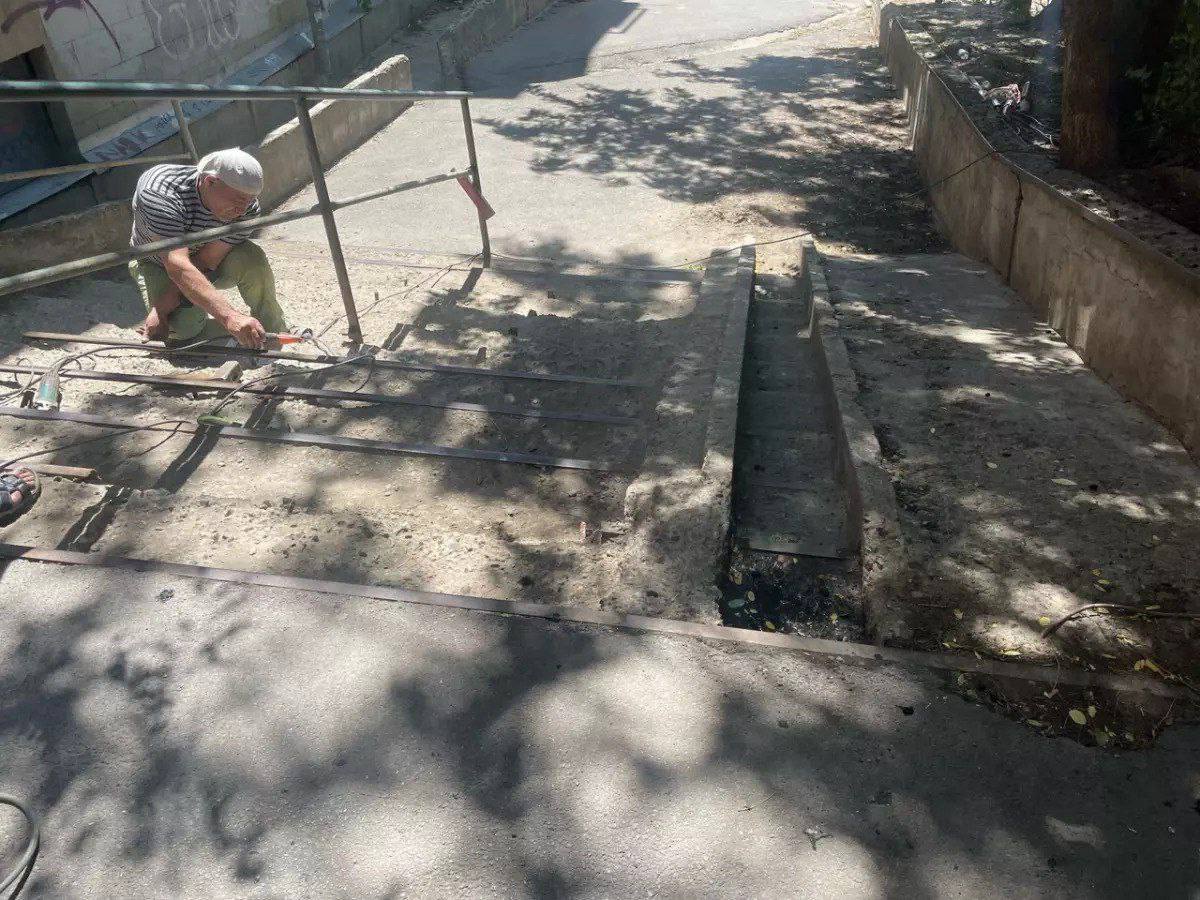 В Ростове спустя два года начали чинить опасную лестницу на Чехова. В районе улицы Красных Зорь и Седова коммунальщики наконец-то добрались до лестницы, на которую ростовчане жаловались с 2023 года. Днем 1 июля рабочие оградили спуск сигнальной лентой и начали ремонт. Местные жители не скрывают удивления — лестница разваливалась буквально на глазах, там постоянно кто-то падал. Сломанные перила, разбитые ступеньки, всё ржавое — пользоваться было опасно. Но обращения в инстанции долго не давали результата. После публикаций в прессе лестницу всё же взяли на баланс в Кировском районе. Правда, ремонт начался только сейчас — через два года после обращений. Новости №1 в Ростове Прислать новость/фото