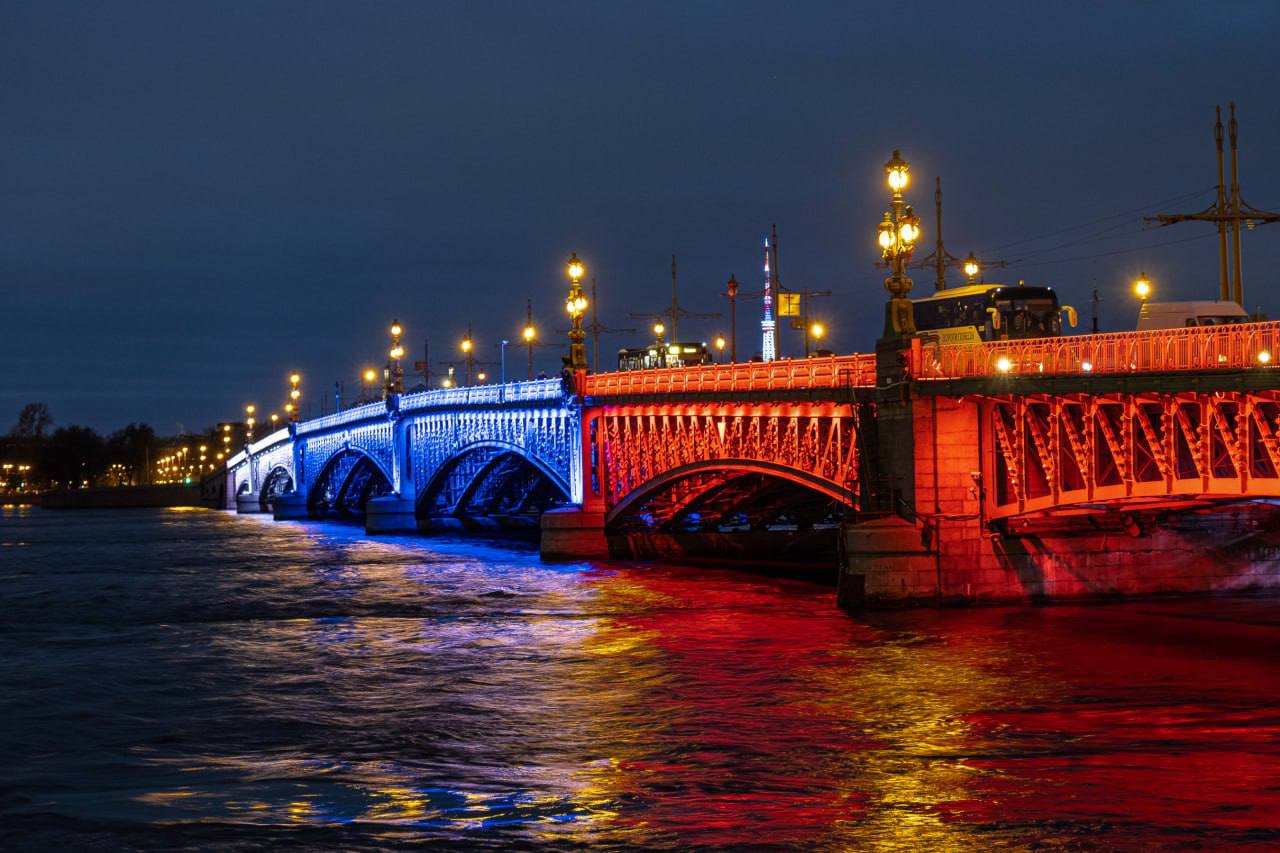 Петербургские мосты засияют в честь 8 Марта  В праздничный вечер мосты Дворцовый, Троицкий и Бетанкура украсят огни в цветах триколора. Подсветка будет работать с 18:50 до 7:30 утра.    Губернатор Александр Беглов отметил, что это решение символизирует важную роль женщин в сохранении традиций и ценностей.