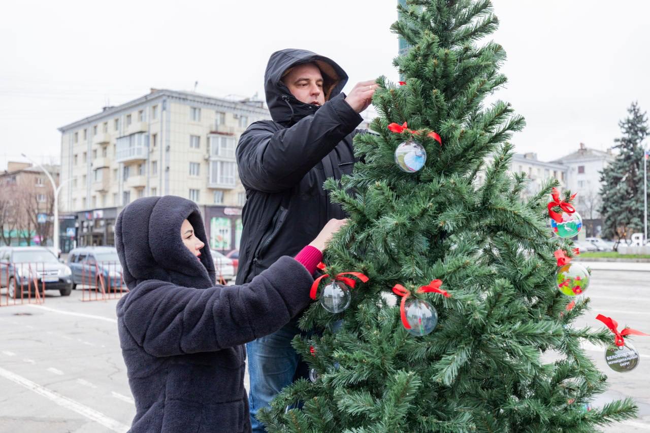 Жители Антрацита и Беловодска первыми украсили елки своих округов на центральной площади в столице ЛНР. Об этом с места события передает корреспондент ЛИЦ.  По задумке, «золотой» шатер главной елки Республики озарит новогодние деревья 27 территорий Луганщины, расположенные вокруг нее. Первыми в композиции появились зеленые красавицы Антрацитовского и Беловодского округов, украшенные игрушками с изображением достопримечательностей территорий.  «Каждый шар оформлен в цветах российского флага. В них отражены наши значимые, ключевые, исторические места. То есть, каждый сможет увидеть в наших украшениях частичку Антрацитовского муниципального округа», — сказал глава местной администрации Сергей Саенко.