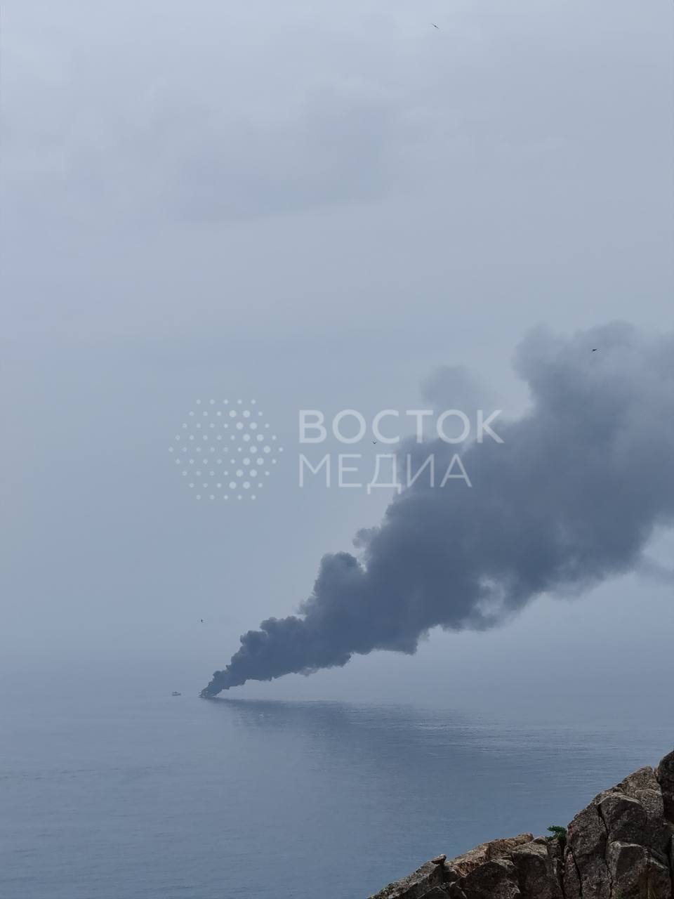 В районе острова Шкота мощно дымит катер Очевидцы предполагают, что на катере произошел пожар. Поднимается огромный столб черного дыма. К месту возгорания подплывает несколько плавсредств.