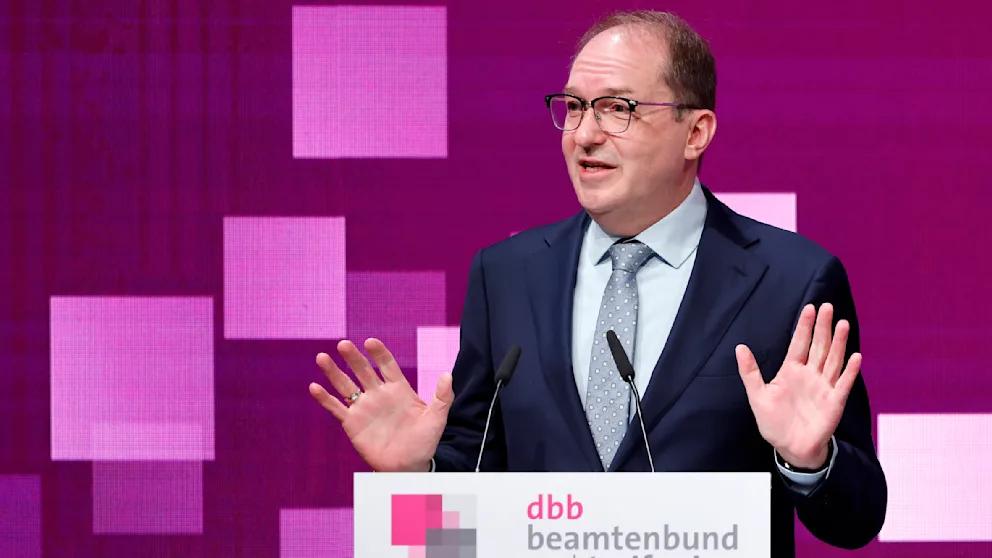 В Германии готовят повышение зарплат сотням тысяч чиновников Федеральное правительство Германии готовит масштабную реформу оплаты труда госслужащих Министр внутренних дел Александр Добриндт заявил на мероприятии профсоюза госслужащих Германии что концепция будет представлена в кратчайшие сроки По его словам действующая система оплаты признана судами неконституционной и требует срочной корректировки Речь идет примерно о 350 тысячах федеральных чиновников судей и военнослужащих По данным МВД их выплаты в 2026 году составят около 23 млрд евро но сколько дополнительно придется потратить после реформы власти пока не говорят Проблема в том что минимальная зарплата госслужащих должна быть не ниже 80 медианного дохода по стране этого требует решение Федерального конституционного суда Германии Сейчас базовые оклады этой планки не достигают При этом повышение коснется не только низкооплачиваемых категорий Из за так называемого принципа дистанции рост внизу автоматически тянет вверх всю шкалу это значит что прибавку получат и хорошо зарабатывающие чиновники BILD Russian