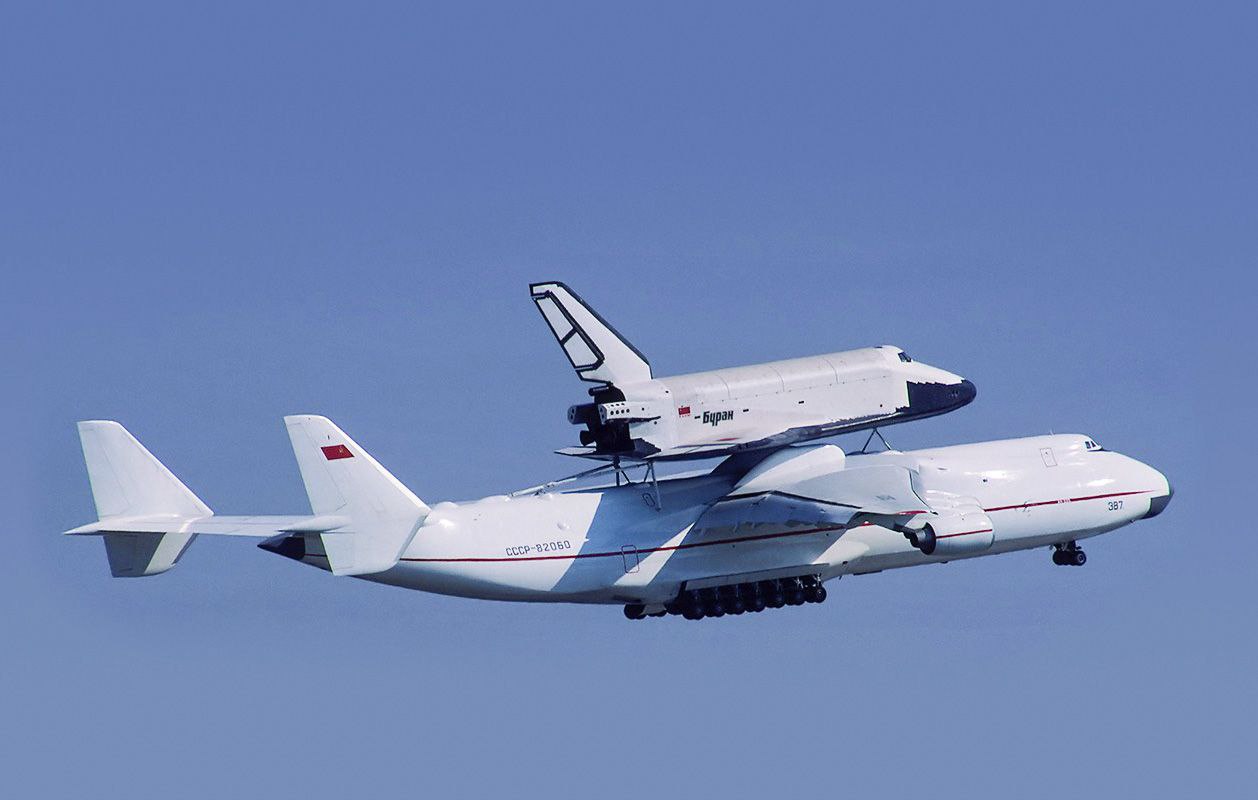 Буран космический тяжеловоз Первый и единственный полёт Буран совершил без груза Он остаётся самым тяжелым отечественным кораблём выведенным на орбиту Давайте опишем его в цифрах Максимальная стартовая масса 105 т 25 легковых автомобилей Длина 36 4 м 1 2 футбольного поля Высота на шасси 16 5 м пятиэтажный дом Размах крыла почти 24 м 2 городских автобуса Советский челнок мог транспортироваться только на специальных самолётах самом грузоподъемном в мире Ан 225 и транспортном ВМ Т ЗМ Т Атлант На фото Буран на самолете Ан 225 Мрия во время демонстрационных полетов в Ле Бурже