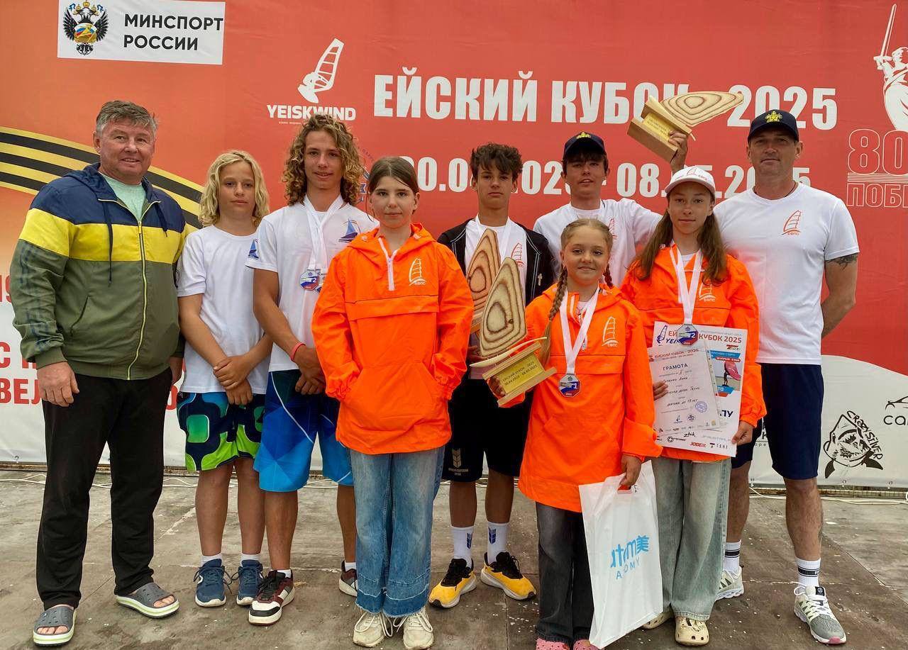 В Ейске завершились межрегиональные соревнования по виндсерфингу «Ейский кубок 2025». Для участия в соревнованиях в Ейск приехали более 160 спортсменов из 12 регионов России, чтобы продемонстрировать свои навыки и таланты в этом захватывающем виде спорта. Погода порадовала участников теплым солнцем и разнообразными ветровыми условиями. Отличные результаты показали ейские спортсмены. В классе парусная доска «Техно»: Дейнега Андрей стал первым среди юношей до 17 лет; Васильев Семён одержал победу среди юношей до 19 лет; Адонин Лев завоевал серебро среди юношей до 19 лет. В классе парусная доска «Фанборд» среди мужчин серебряную медаль завоевал Адонин Лев. В классе «Техно» среди девушек до 13 лет: абсолютным лидером стала Васильева Василиса, обогнав даже всех мальчиков; серебряную медаль завоевала Питенко Анна.