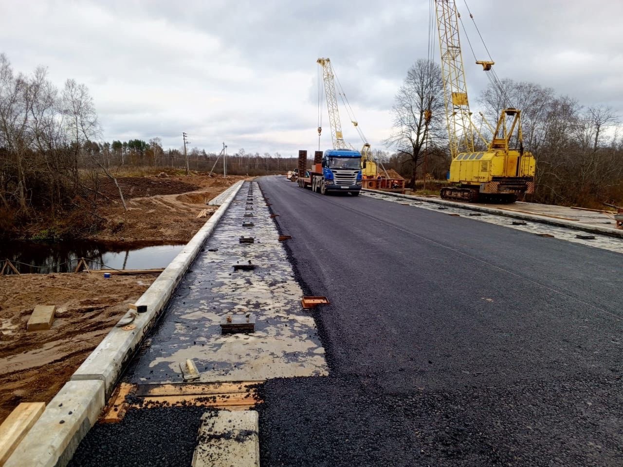 ⌛  Завершается ремонт моста через Ловать в Великолукском районе  Близятся к завершению работы по реконструкции моста через реку Ловать на автомобильной дороге «Борки-Стайки» до деревни Сивцево, которые выполняются подрядной организацией ООО «Автомобильные дороги Пскова». Об этом сообщил глава Великолукского района Алексей Кузьмин на своей странице ВКонтакте.  На данный момент идет укладка асфальта, а также выполняются работы по обустройству откосов конусов, водоотвода и разборка временного моста.